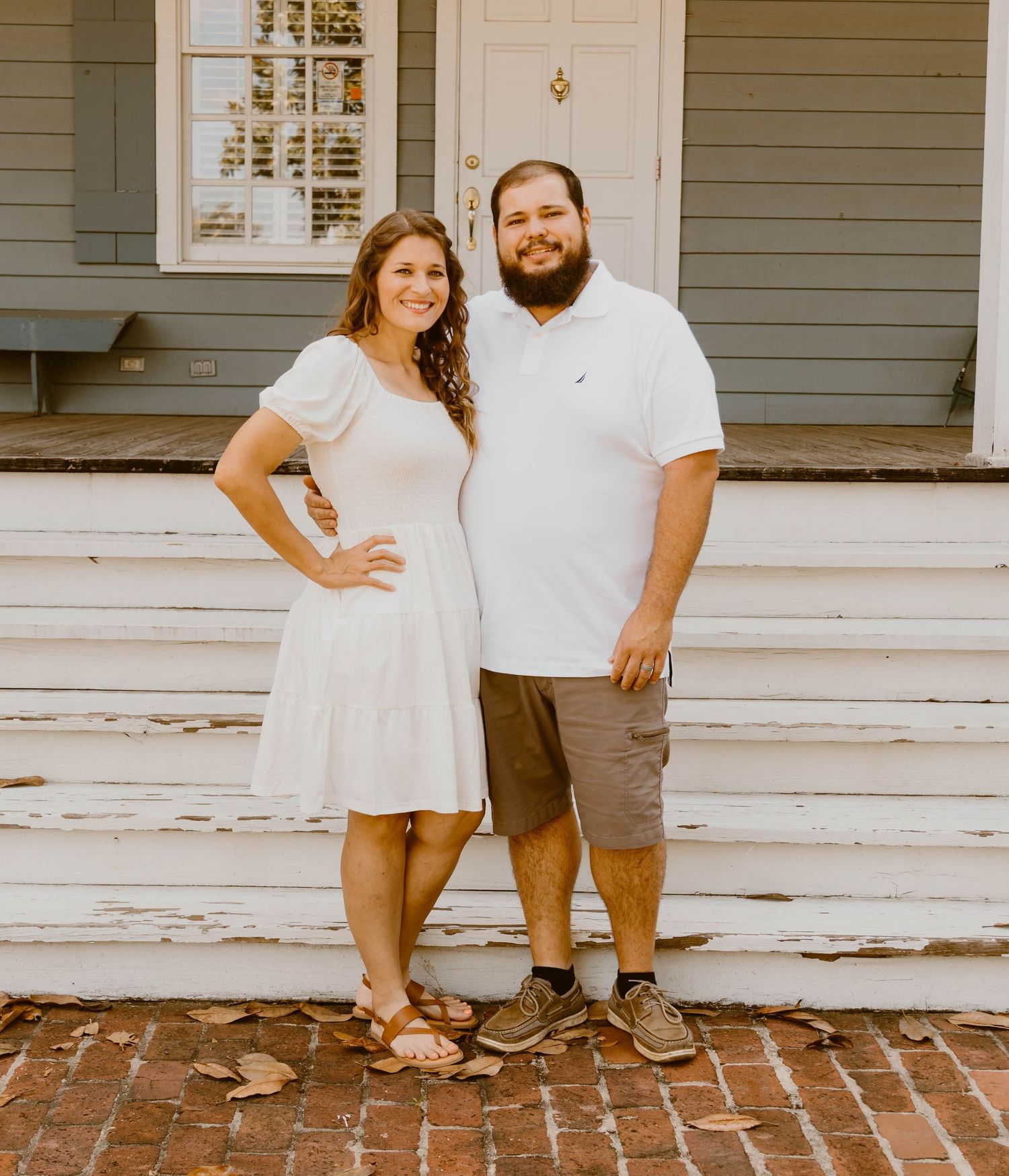 Family portrait on brick walkway in front of gray house with white trim.