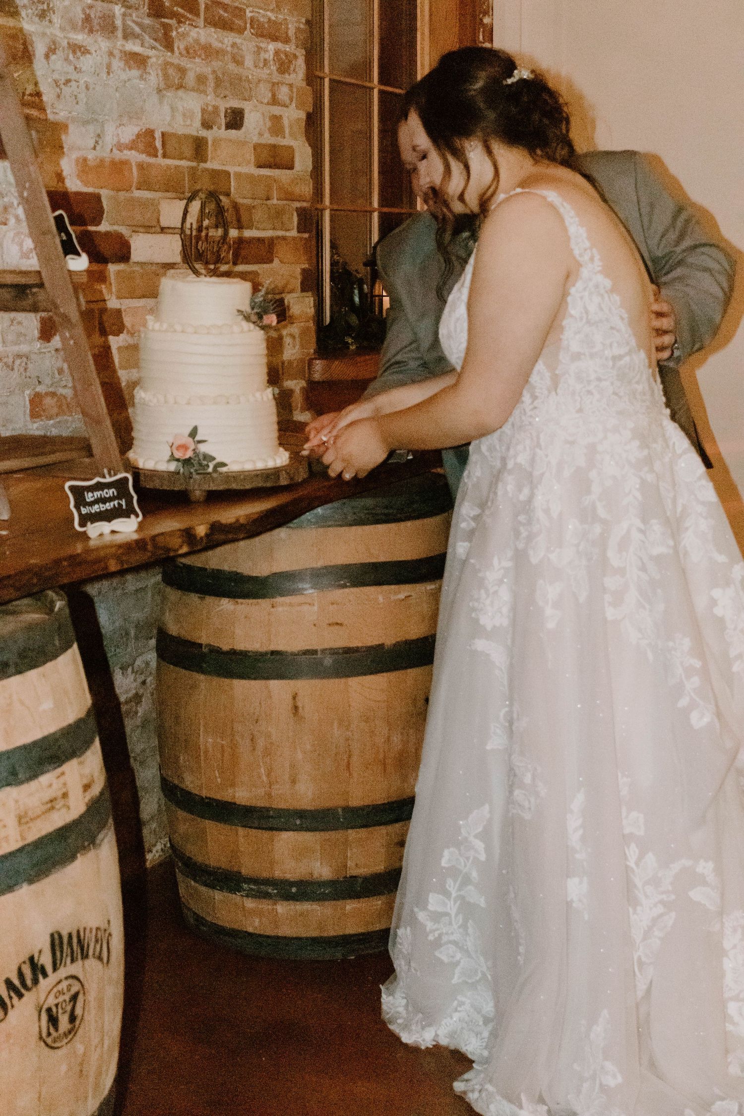 Wedding celebration details with rustic wooden barrels and flowing white dress in a brick venue.