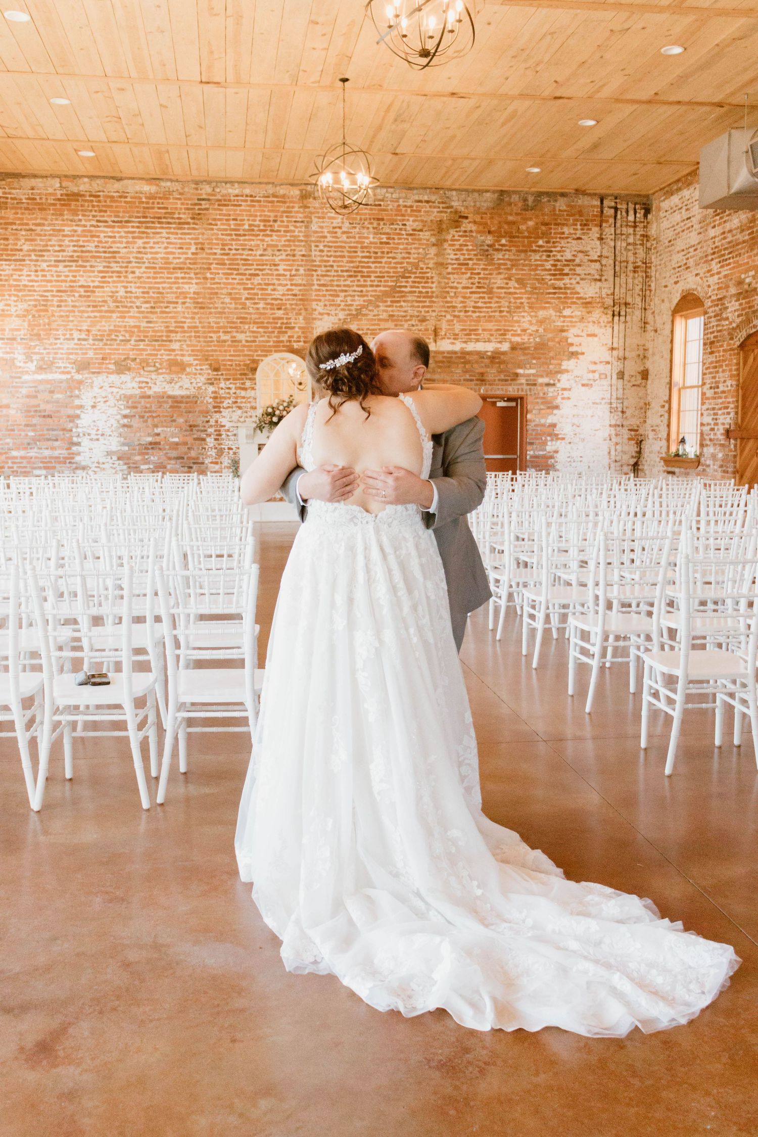 Empty wedding ceremony venue with white chairs and exposed brick walls.