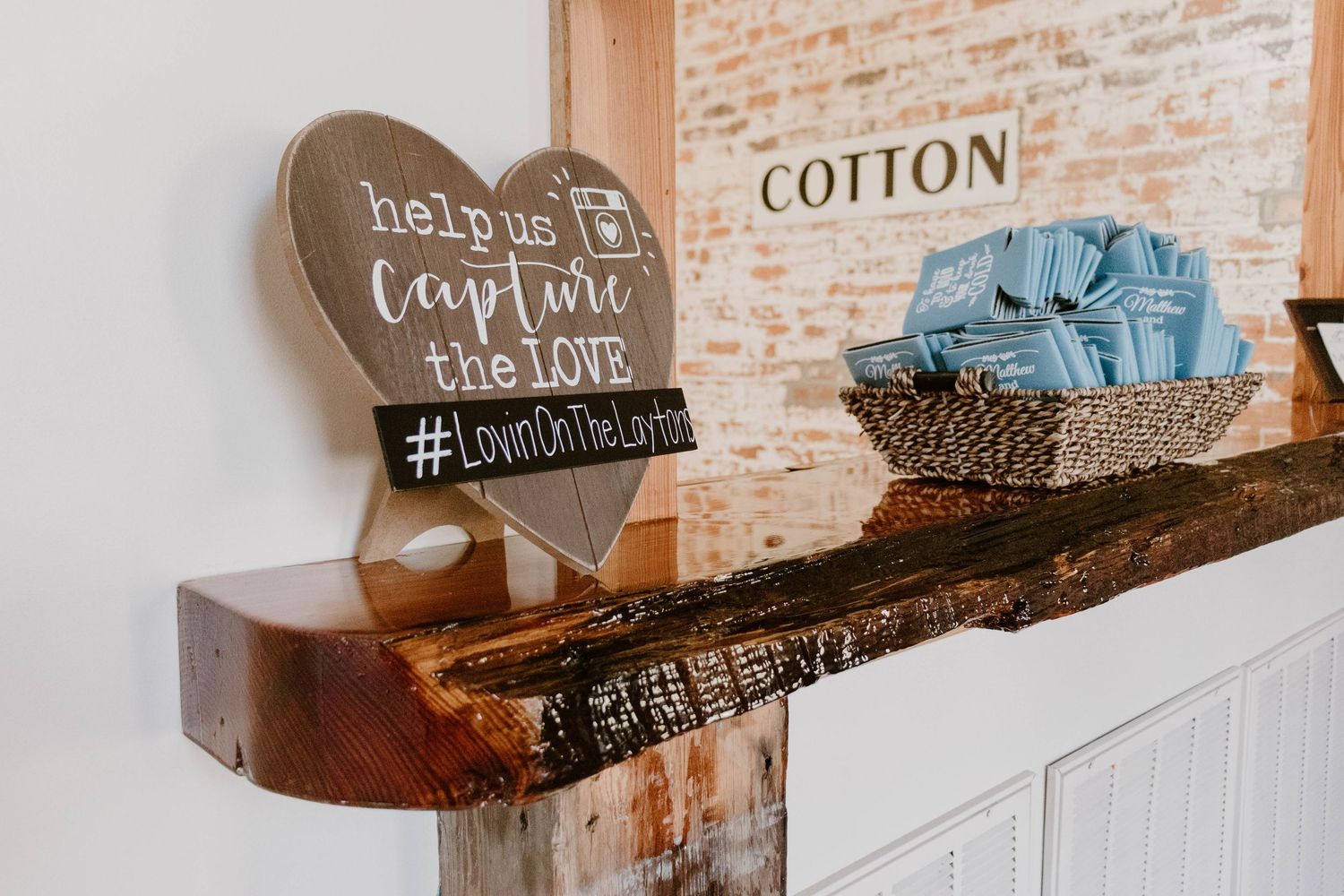 Rustic wooden shelf with farmhouse style decor and signs mounted on exposed brick wall.