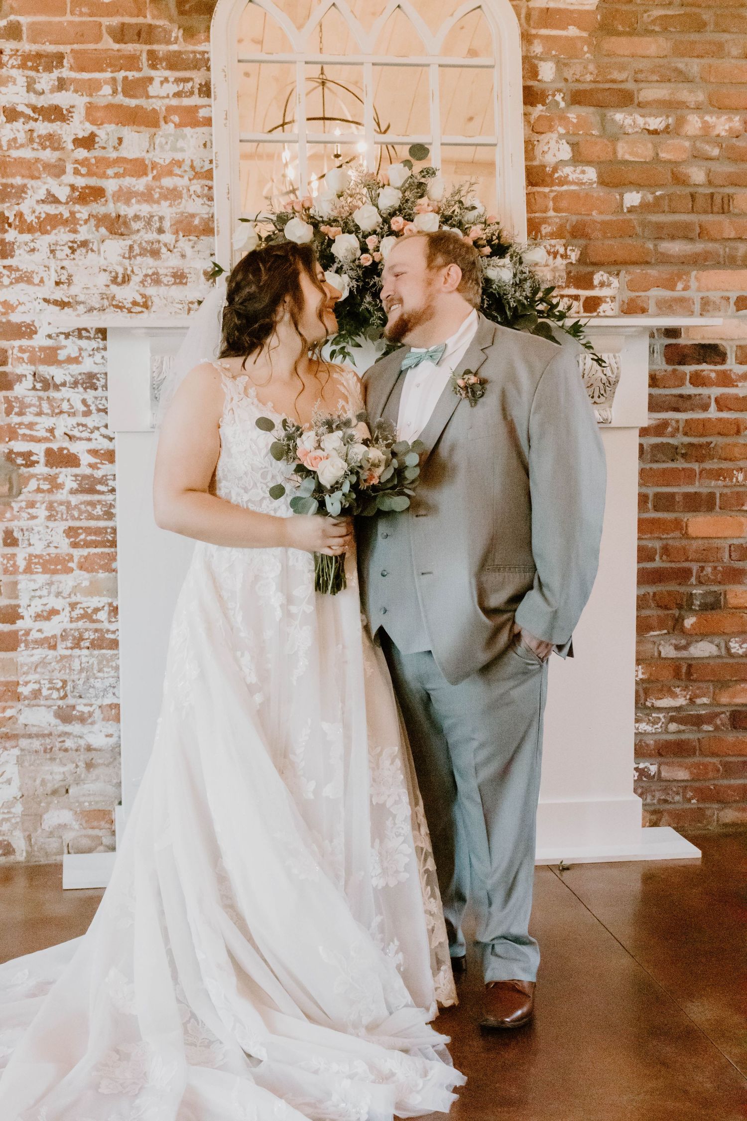 Elegant wedding portraits against rustic brick backdrop with white floral bouquets.