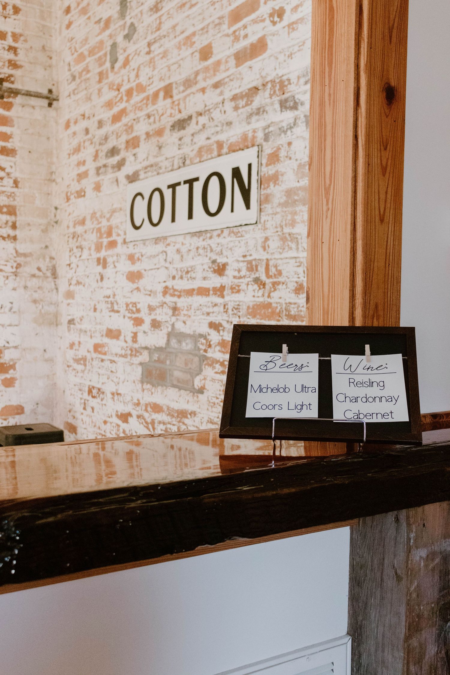 Cotton sign mounted on exposed brick wall with informational cards displayed below.
