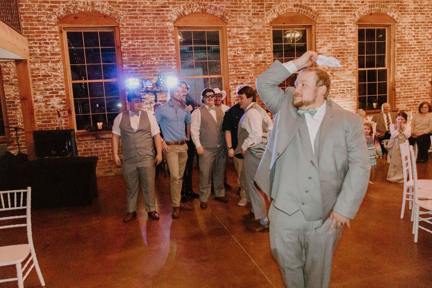 Evening wedding reception in a historic brick venue with guests dancing and celebrating.