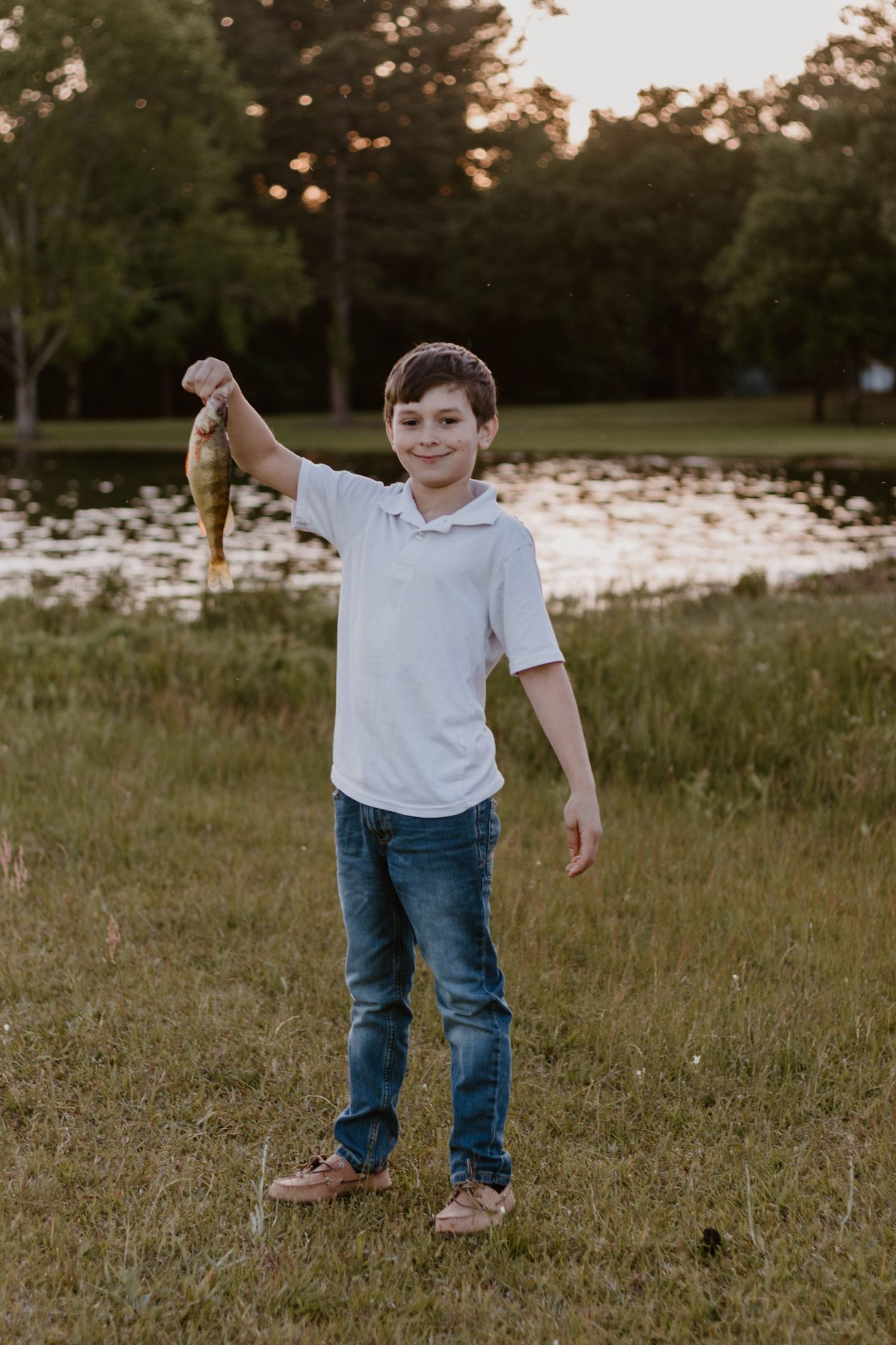 Young child playing and running in grassy field at sunset.