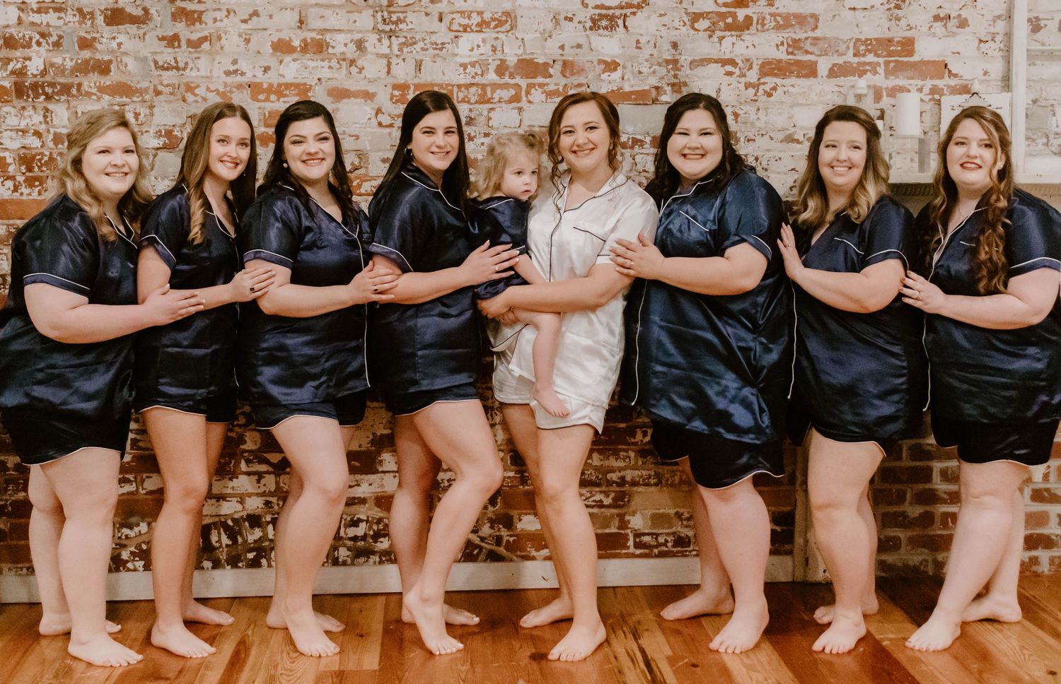 Bridesmaids in black robes show off their bare feet while sitting in a row.