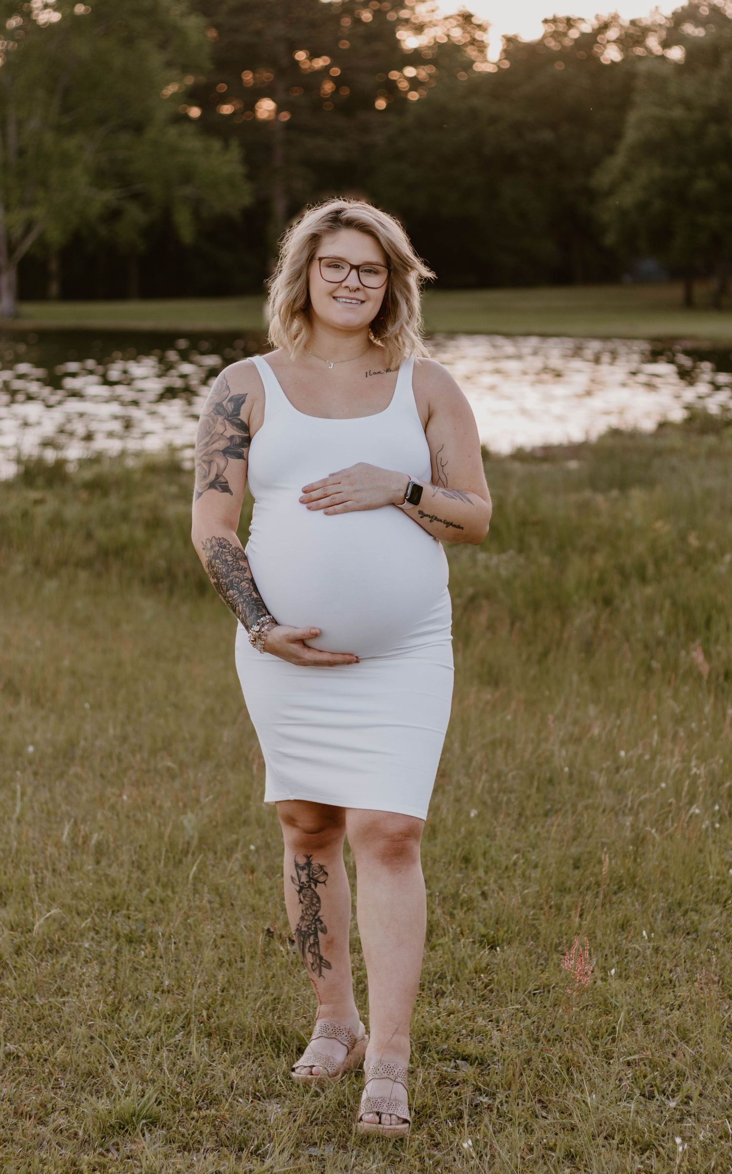 Candid maternity photos taken in field during golden hour.