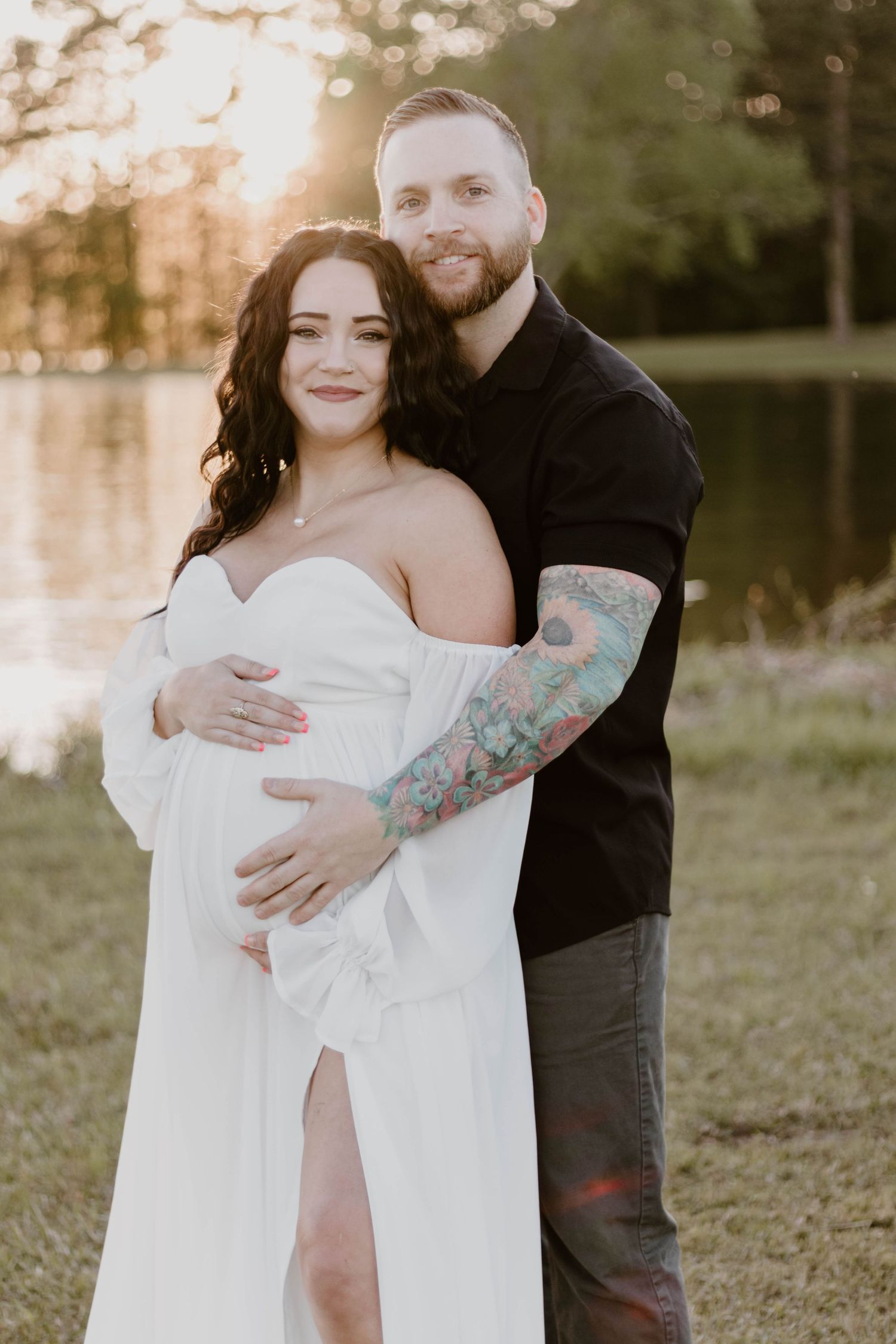 A couple poses together outdoors during a maternity photoshoot at sunset.