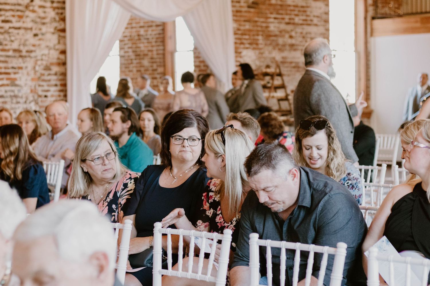 Wedding reception venue with white chairs and exposed brick walls.