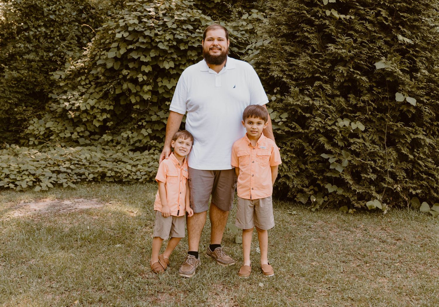 Family members standing together on grass in coordinated casual outfits.