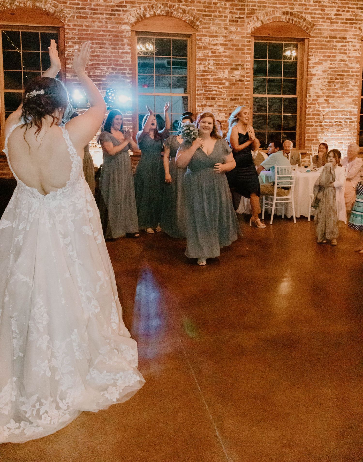 Wedding reception dance floor scene in a rustic brick venue with guests celebrating.