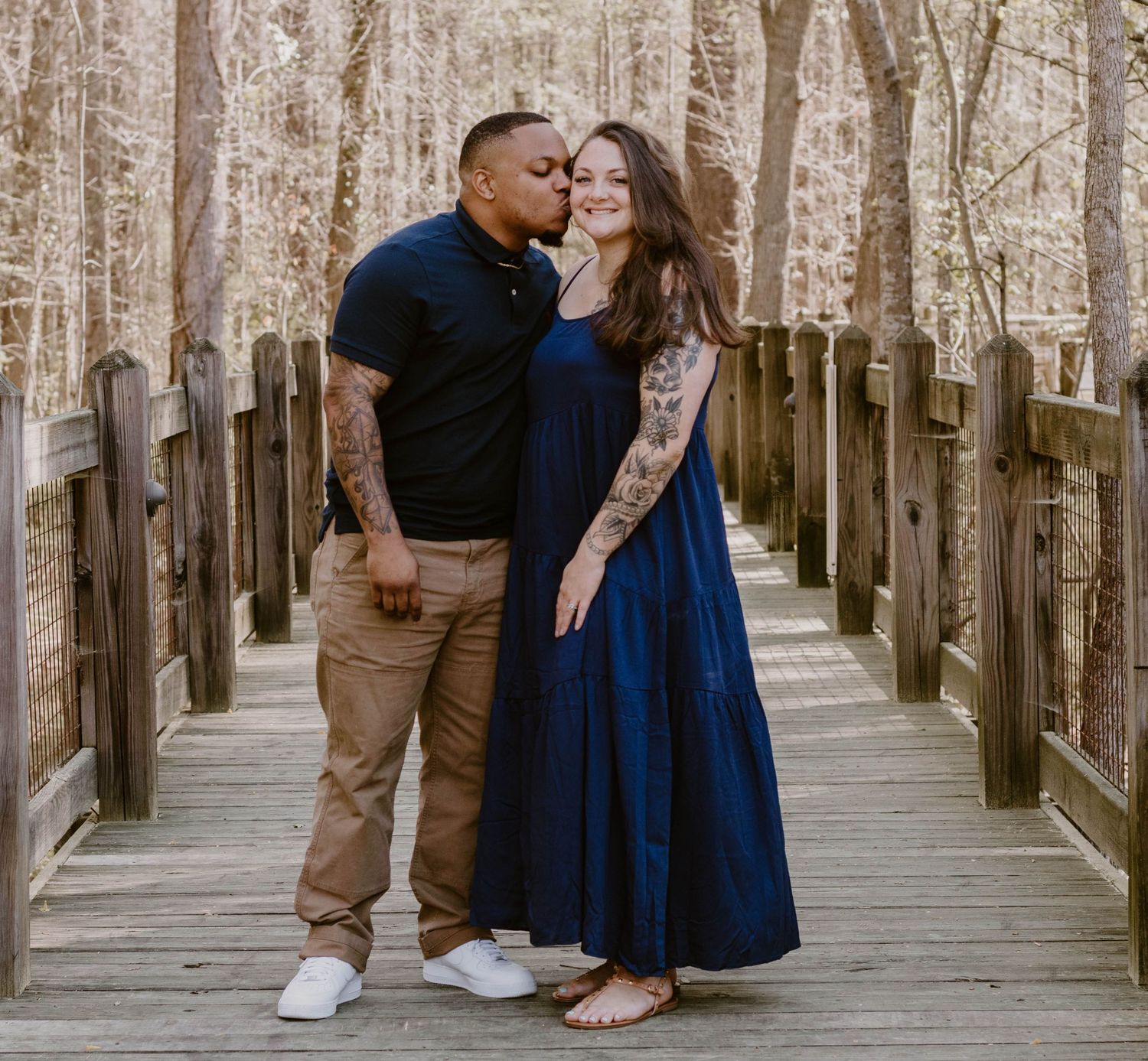 Romantic couple moment captured on a wooden walkway with natural forest backdrop.