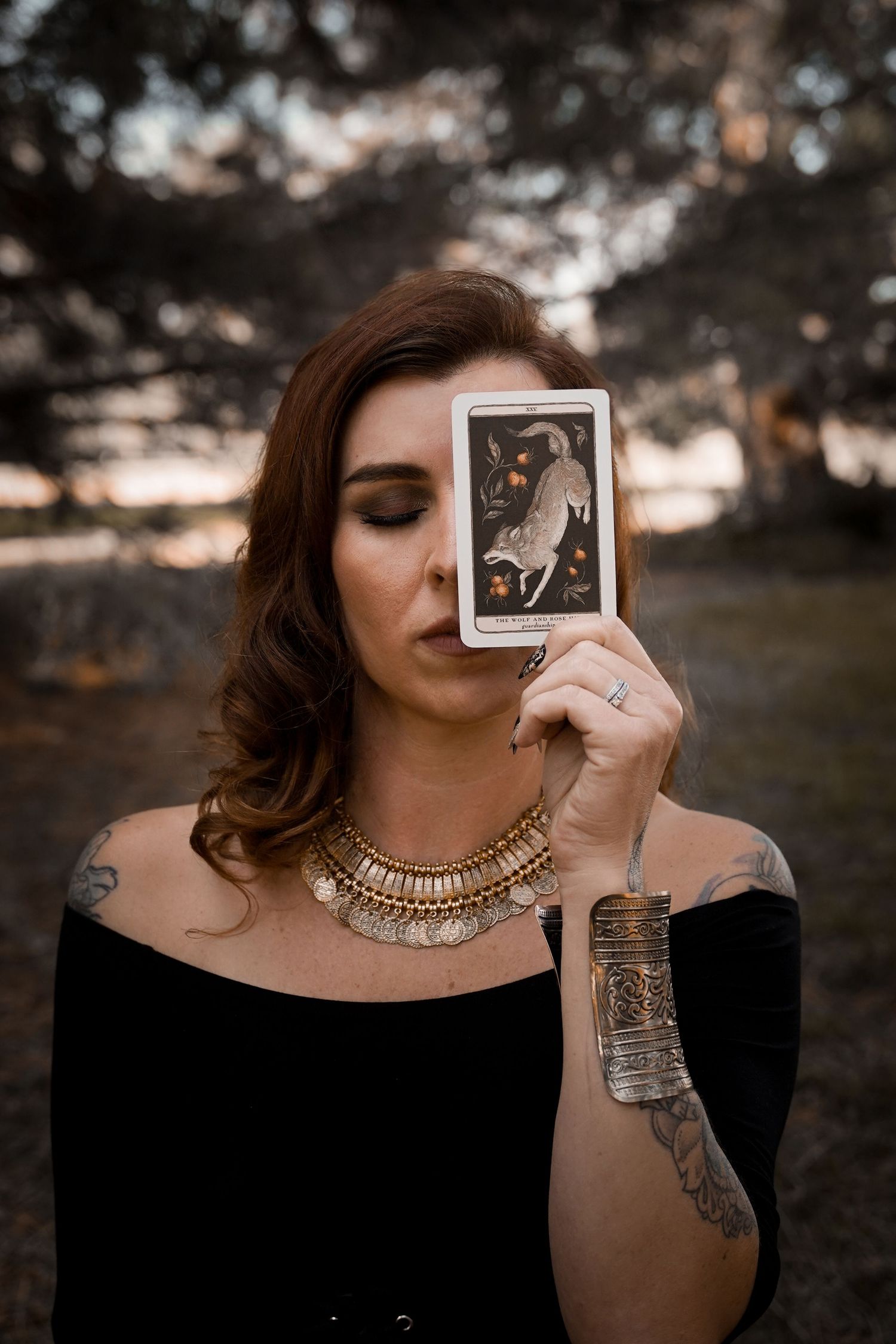 Creative portrait of a woman in black holding a vintage polaroid photo against sunset.