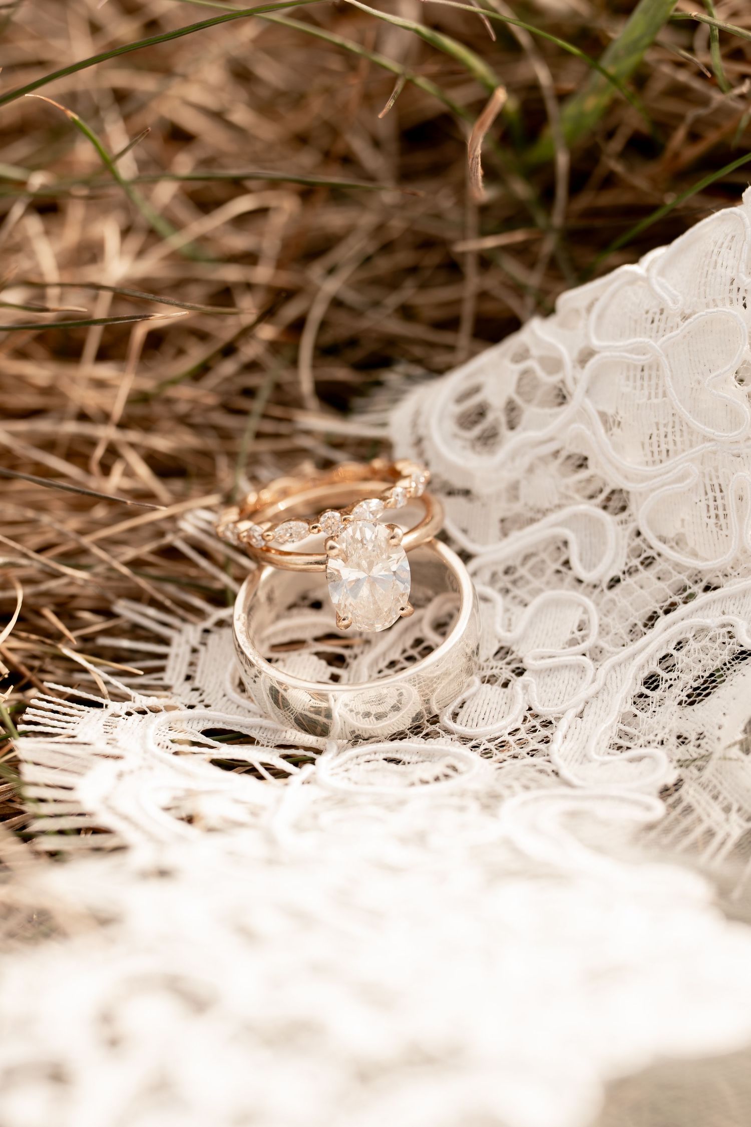 Close-up of a pear-shaped diamond engagement ring and wedding band resting on lace bridal veil.