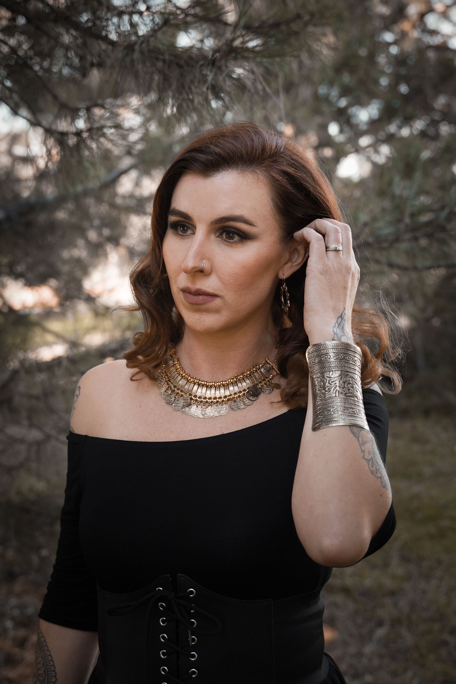 Elegant portrait featuring gold statement necklace and black off-shoulder top.