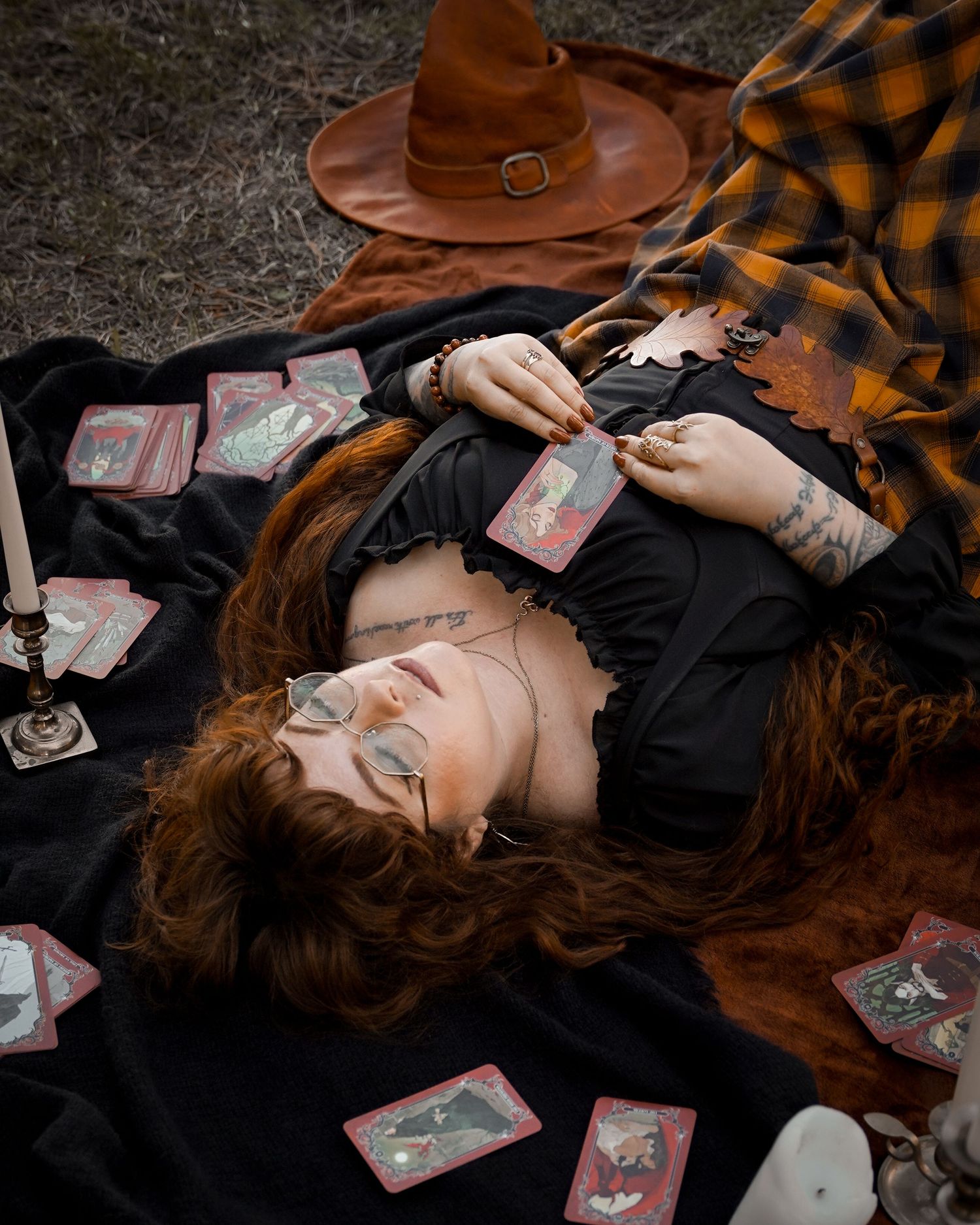 Artistic tarot card reading scene with scattered cards and brown hat on dark background.