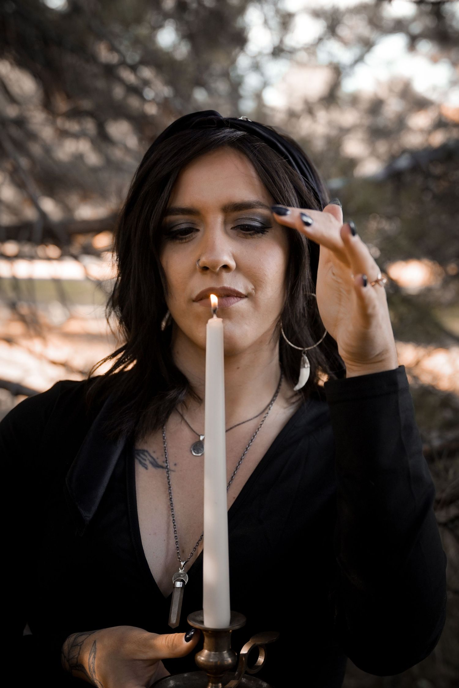 Dramatic portrait series of someone in black clothing lighting and holding a white candle in moody lighting.