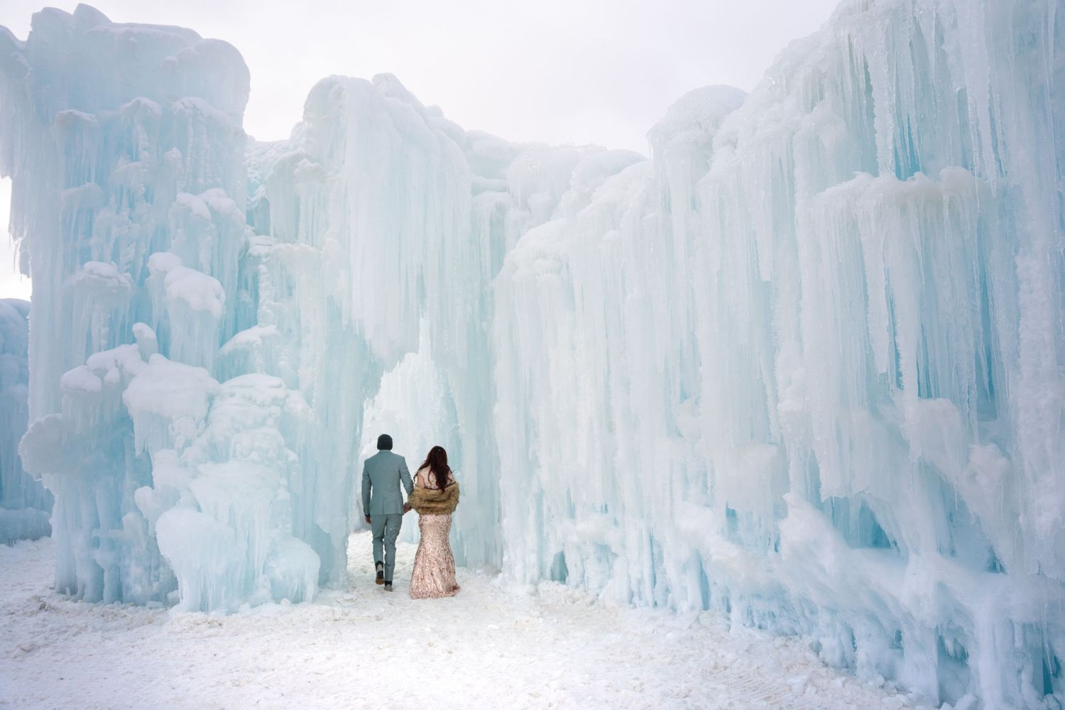 Towering ice castle structures with blue lighting create a magical winter wonderland landscape at night.