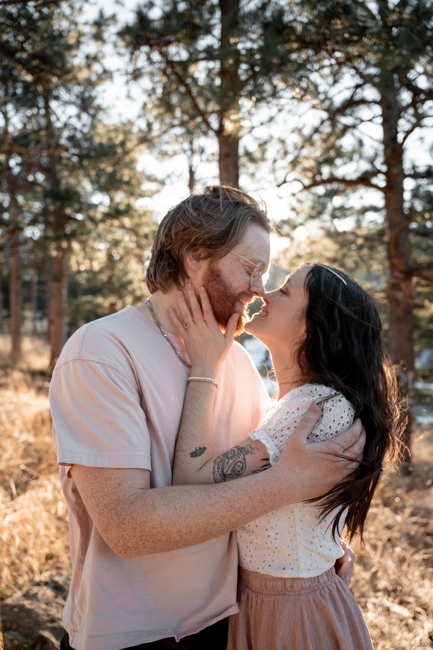 A couple shares an intimate moment during a sunset photoshoot in a natural outdoor setting.