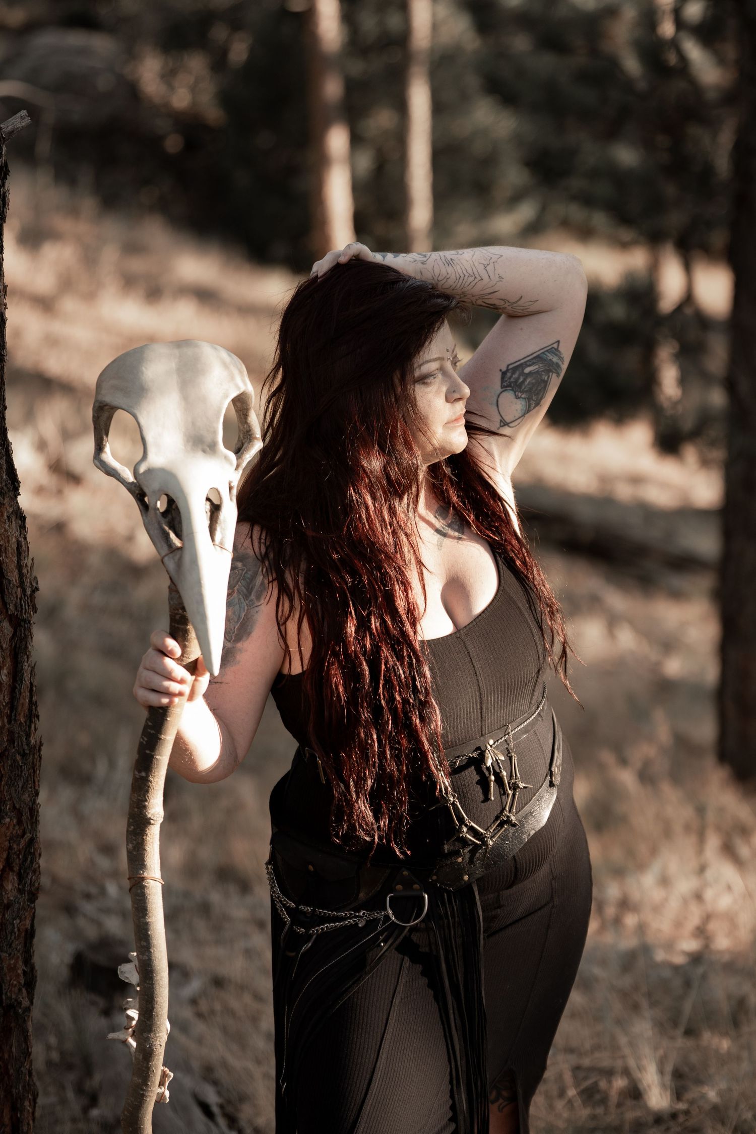 Artistic portrait with a white animal skull prop in a moody forest setting.