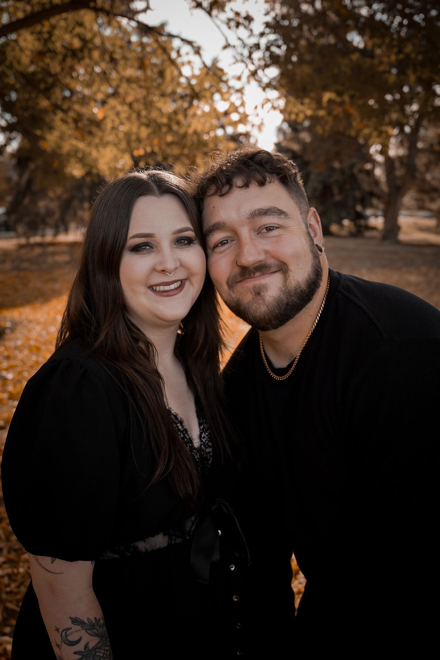 A couple shares intimate moments outdoors during an autumn photoshoot with warm golden lighting and fall foliage.