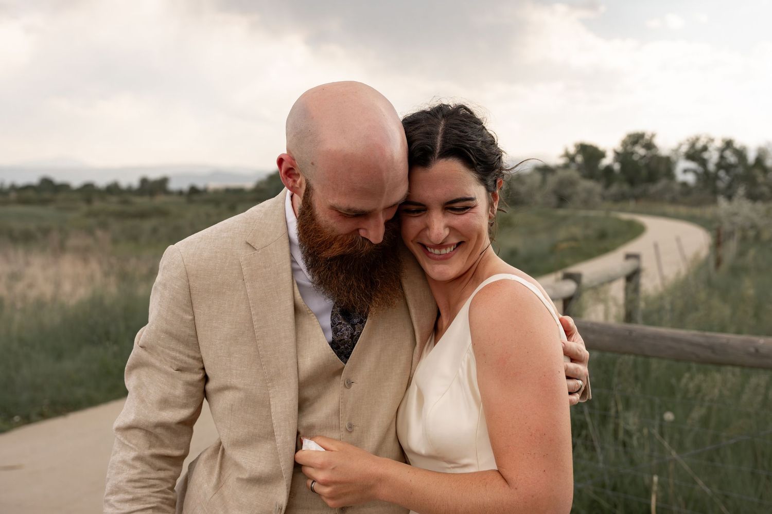 Intimate wedding portrait captured on wooden boardwalk through natural grassland.