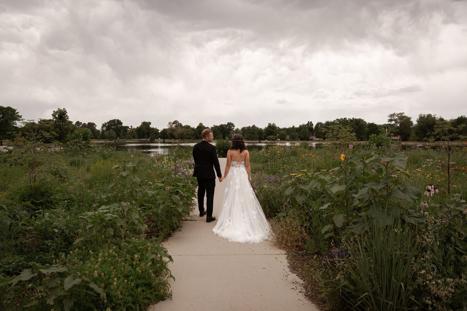 A wedding couple poses in a lush garden setting surrounded by greenery and flowers on their special day.