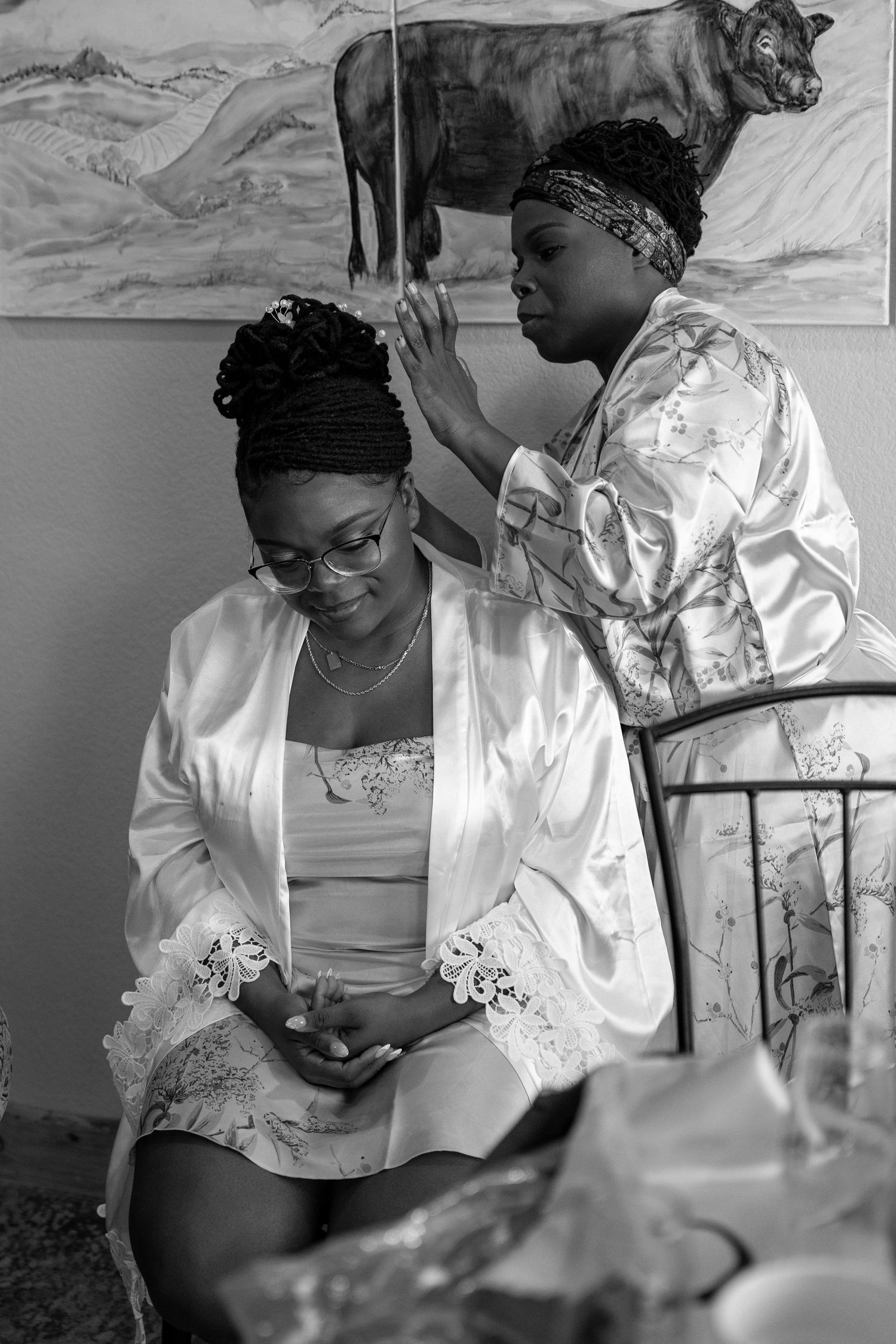 Mom adjusts bride's hair while getting ready.