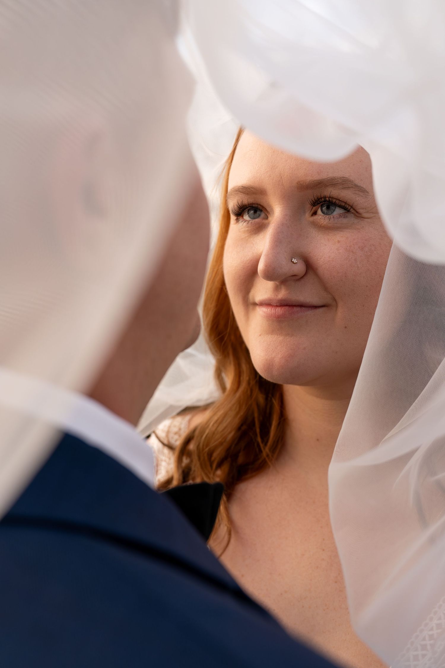 Close-up portrait through wedding veil with soft natural lighting.