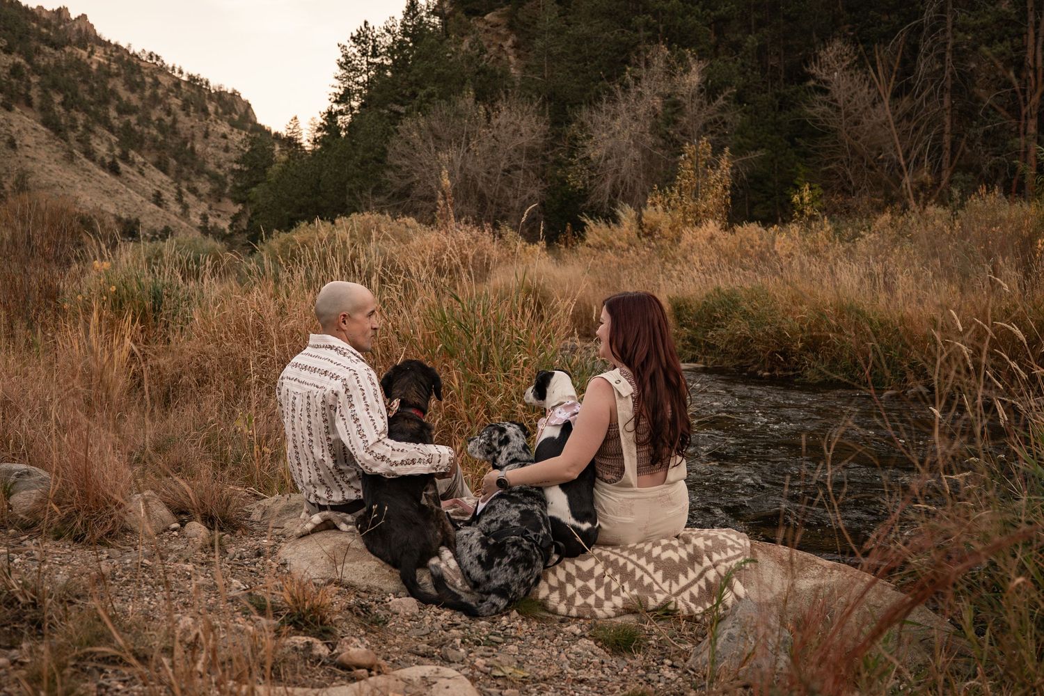 Romantic photoshoot among rocky terrain and dried grass with mountain views at sunset.