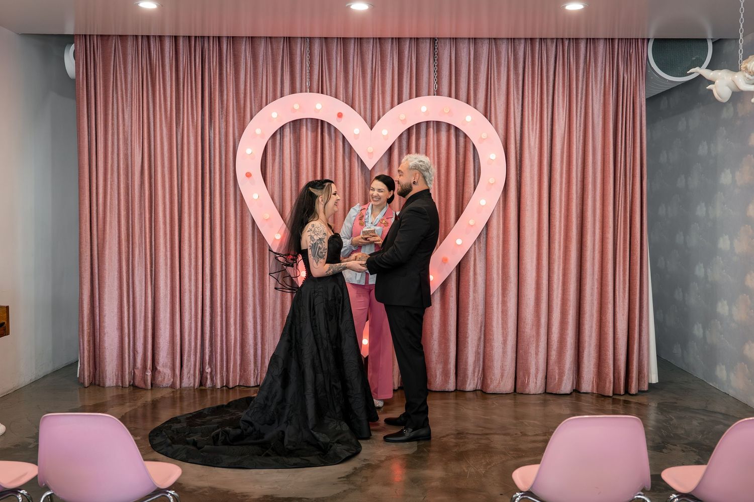 Pink-tinted wedding venue interior with heart decorations and curtains.