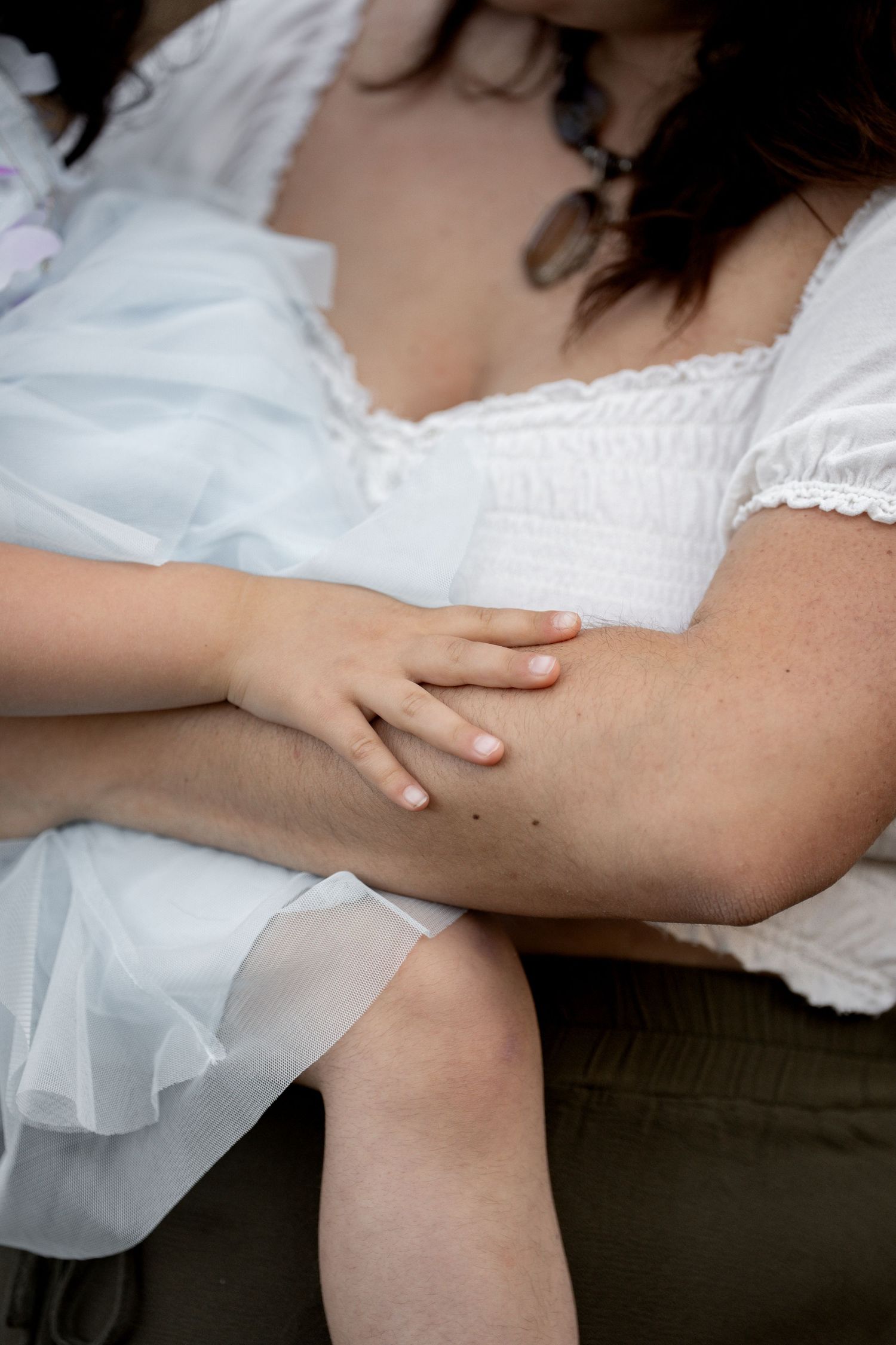 Close-up detail of delicate white lace fabric and hands against a dark background.