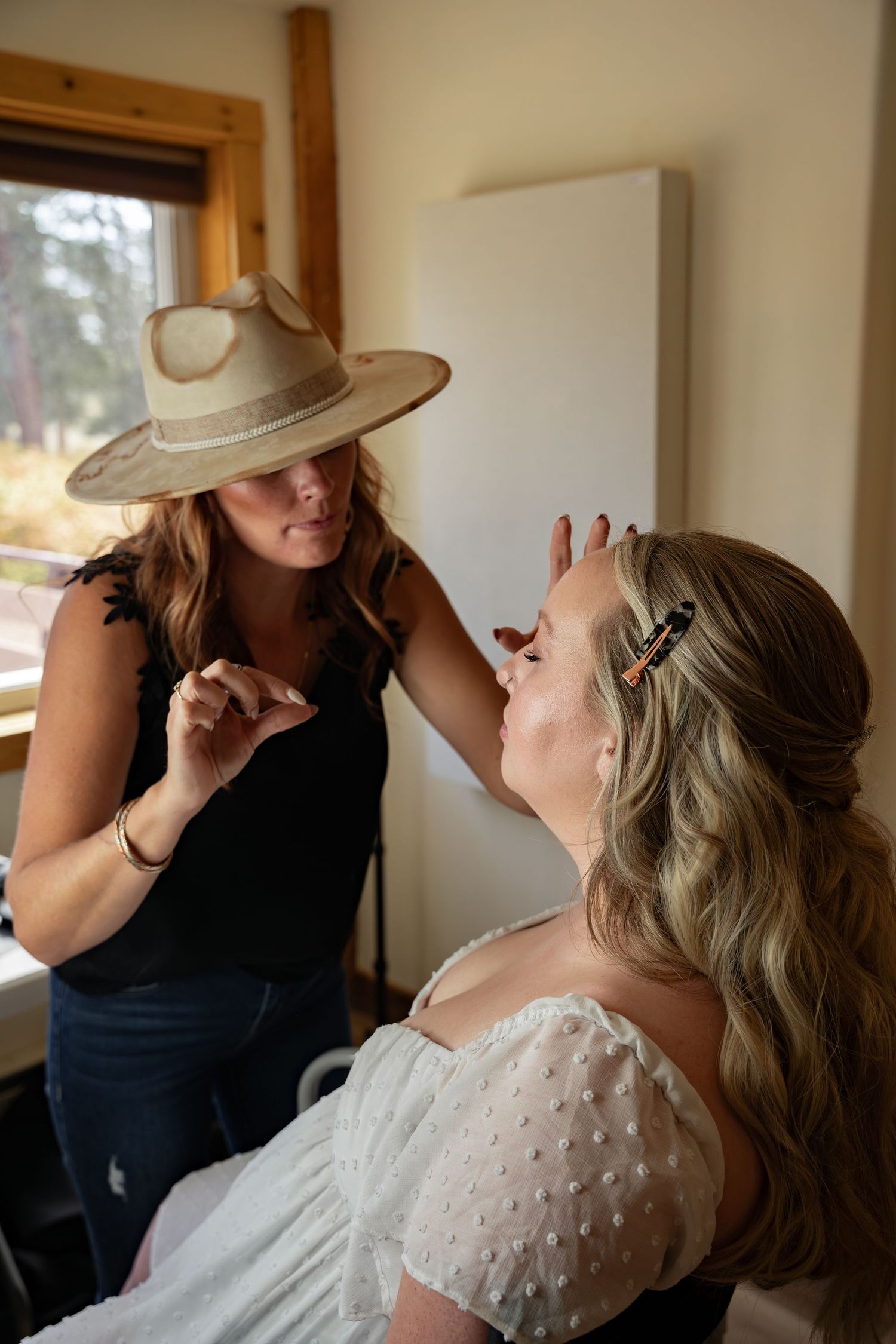 Makeup artist puts finishing touches on bride to be's makeup.