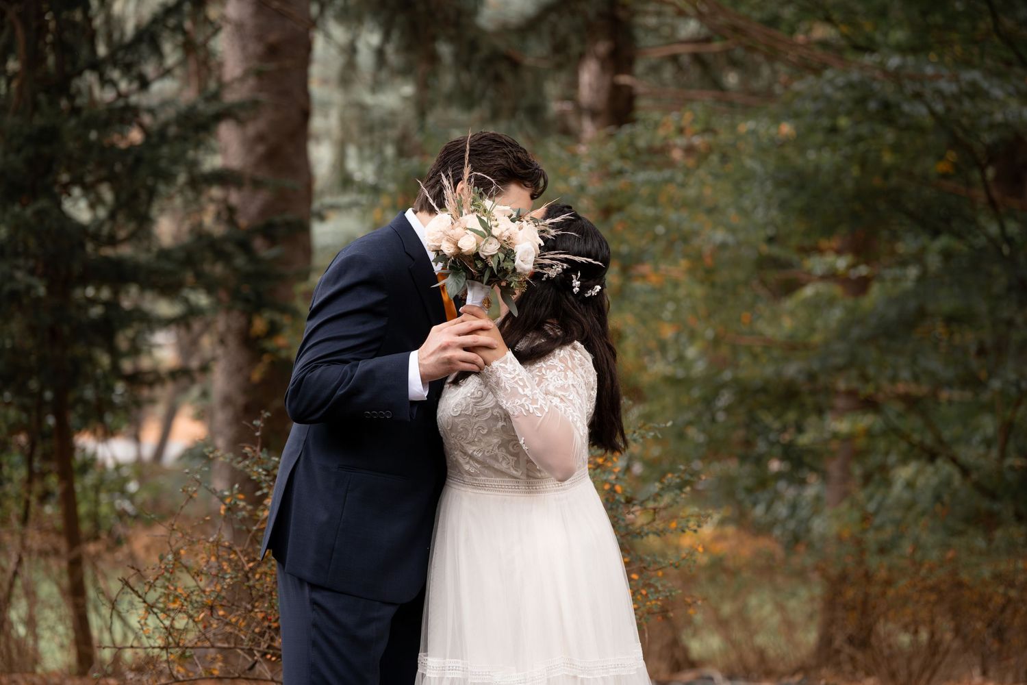 Wedding couple shares intimate moments in a forest setting.