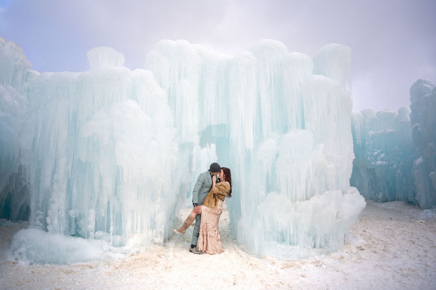 Stunning ice castle formations glowing with ethereal blue light in a winter wonderland setting.