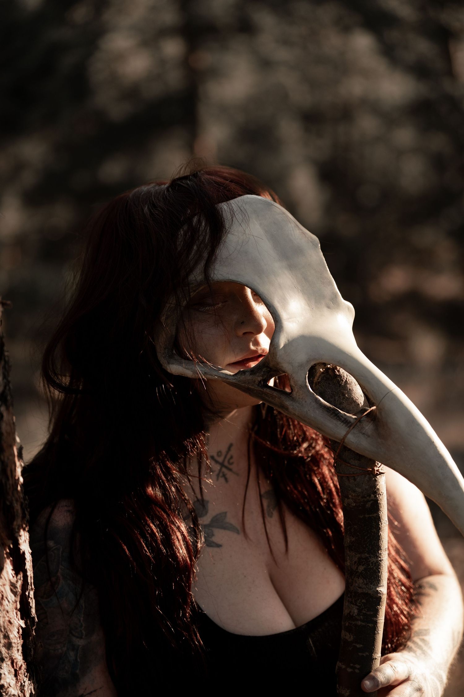 Dramatic portrait session featuring a person holding a white animal skull in dark lighting.