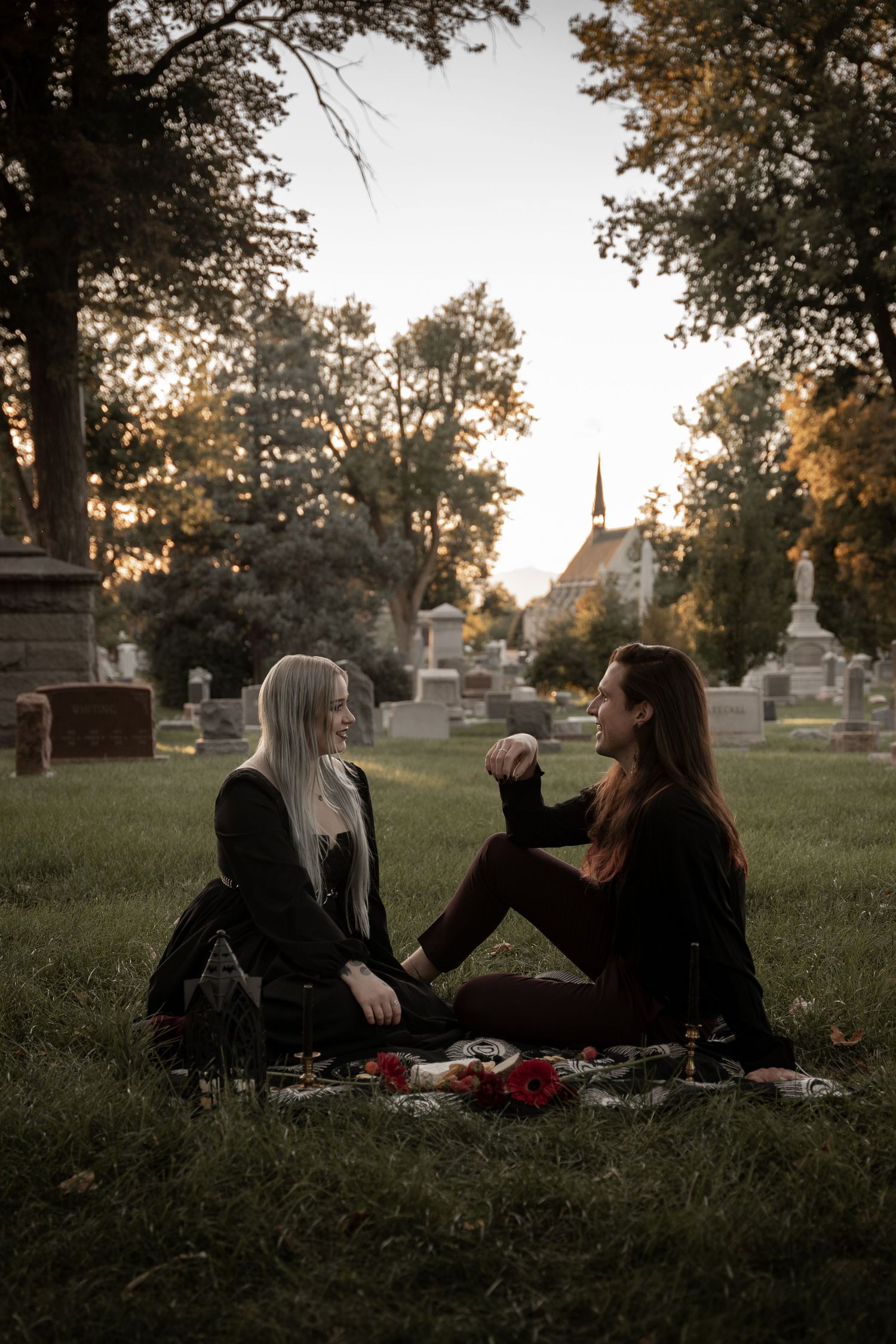 People having a picnic among gravestones at sunset in an old cemetery.