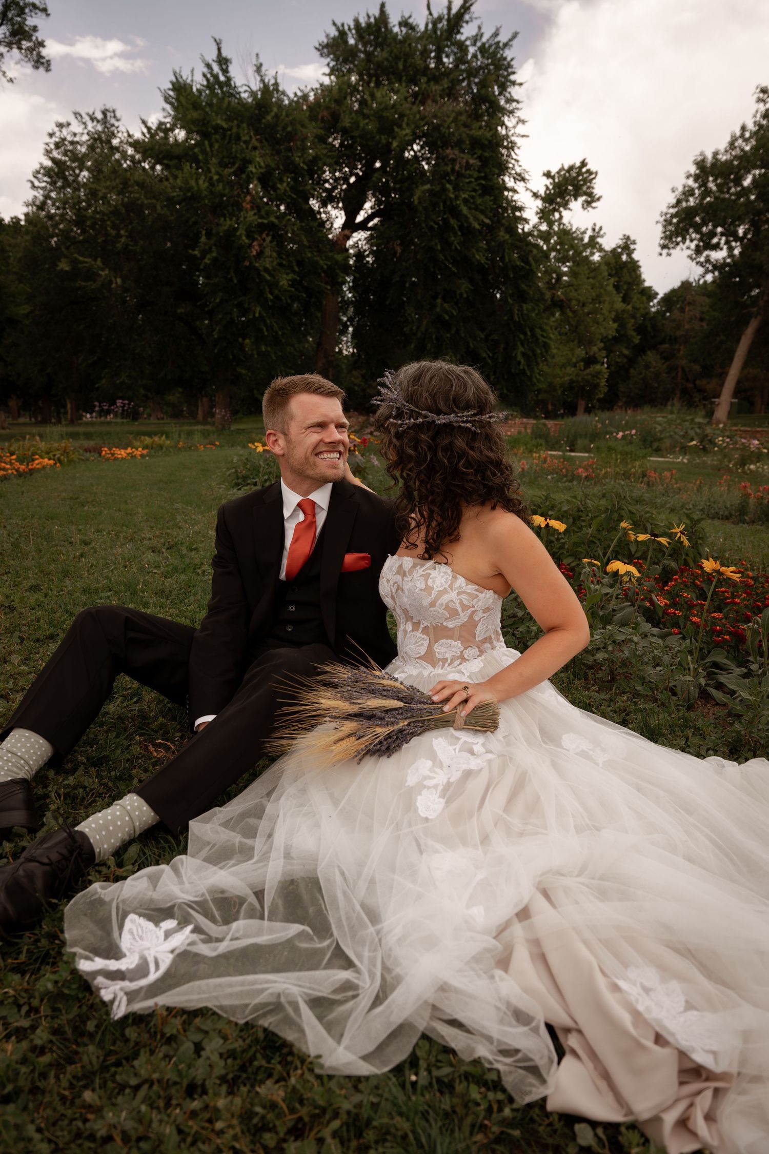 Newlywed couple shares romantic moments in a garden with orange flowers as the sun sets.
