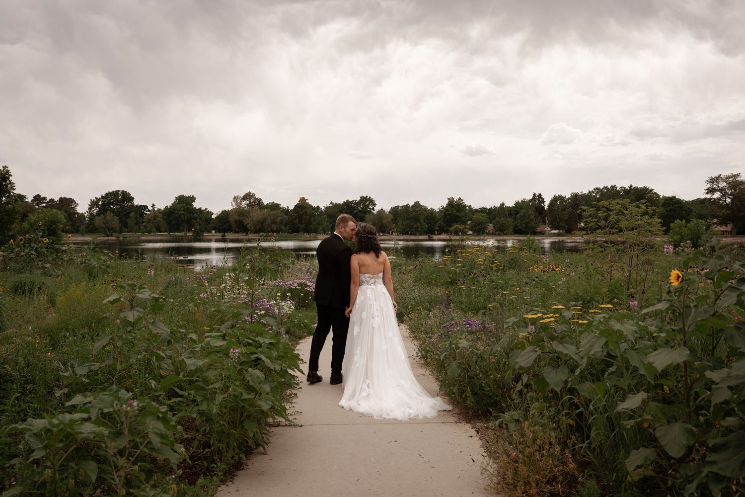 A panoramic view of a wedding ceremony in a lush garden setting with white chairs and floral arrangements.