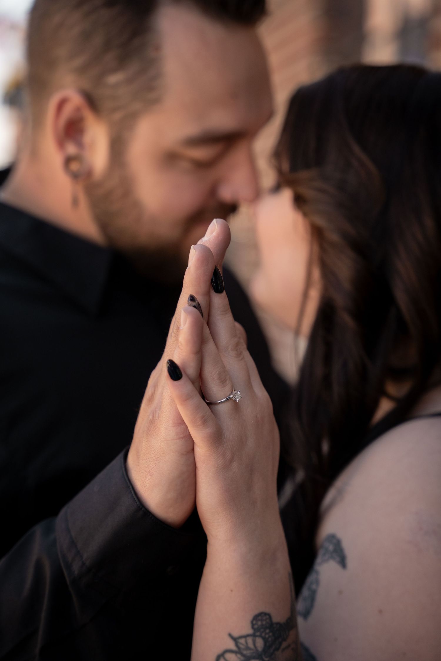 Close-up of hands with engagement ring during an intimate moment.