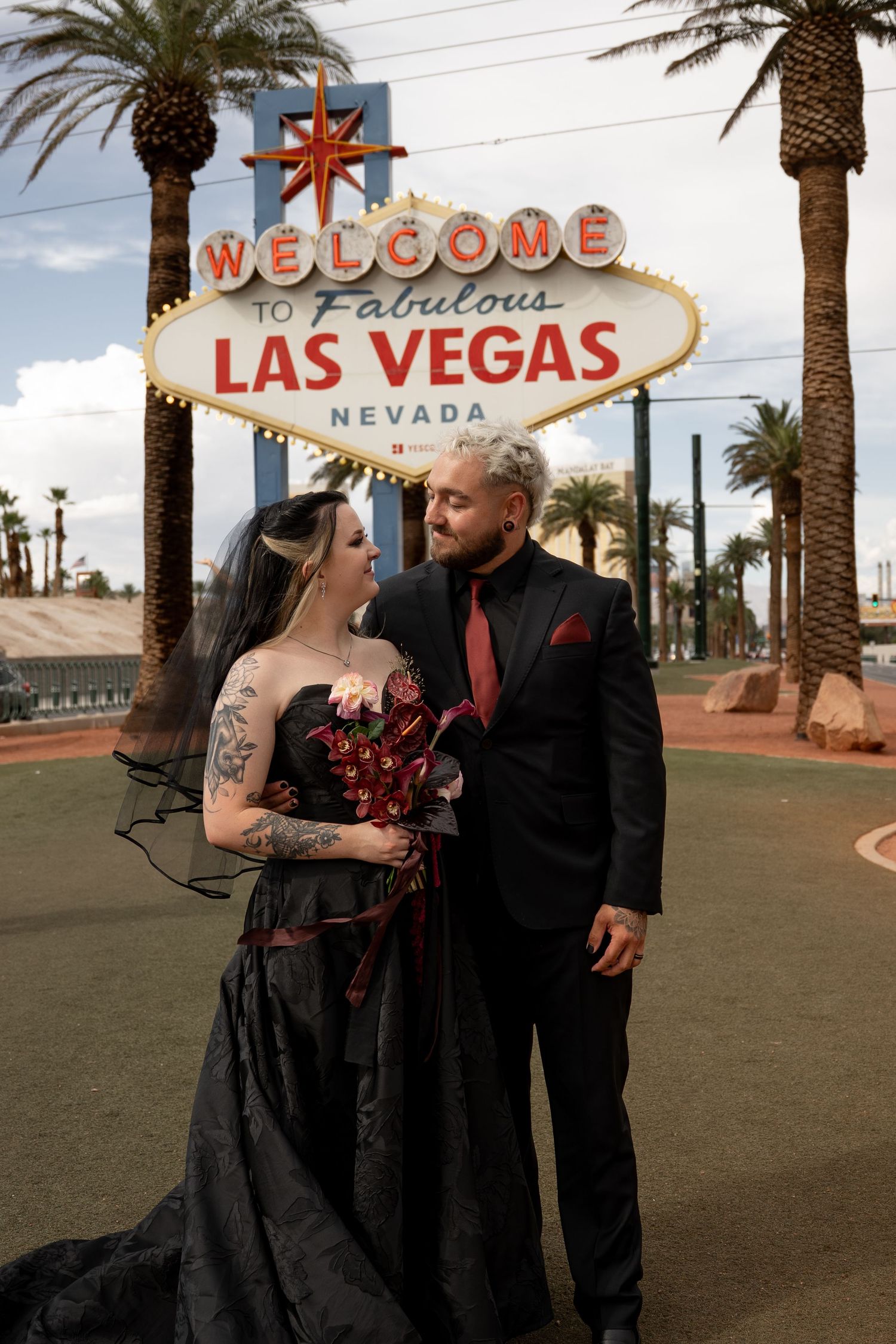 Wedding couple poses near iconic Las Vegas welcome sign with palm trees.