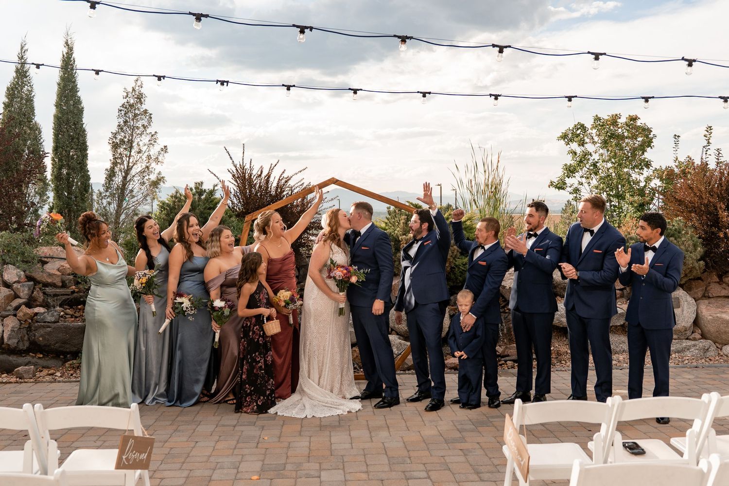 Wedding party celebrates on outdoor patio under string lights.