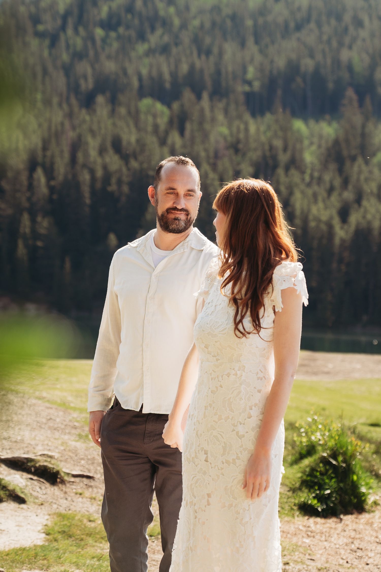 Bride and groom share a quiet moment in soft sunlight, surrounded by forested mountains in Banff, capturing a natural and relaxed wedding.