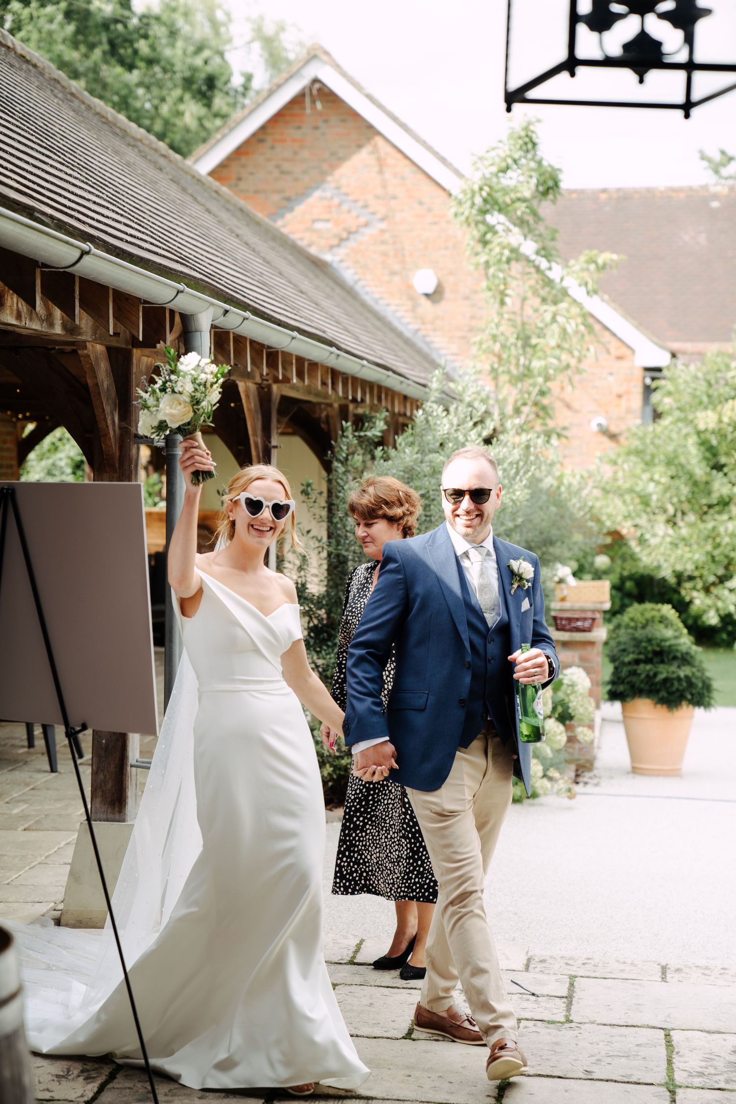 Bride and Groom enter their wedding breakfast, sun glasses on with big grins on their faces, ready to get the part started.
