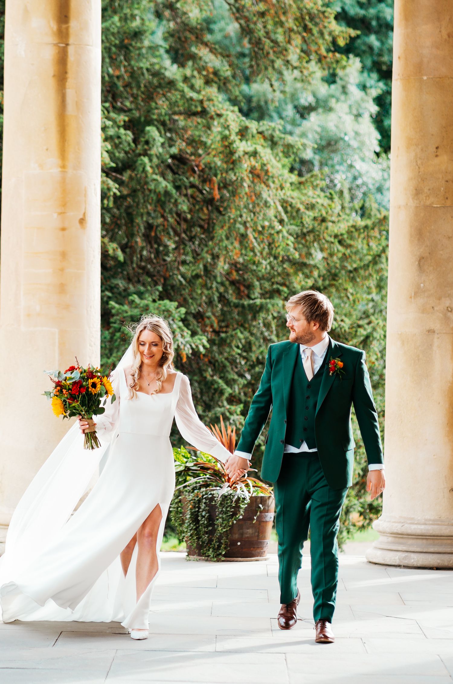 Bride & Groom walk between two pillars conveying their emotions and thoughts between one another as they leave the church form the ceremony.