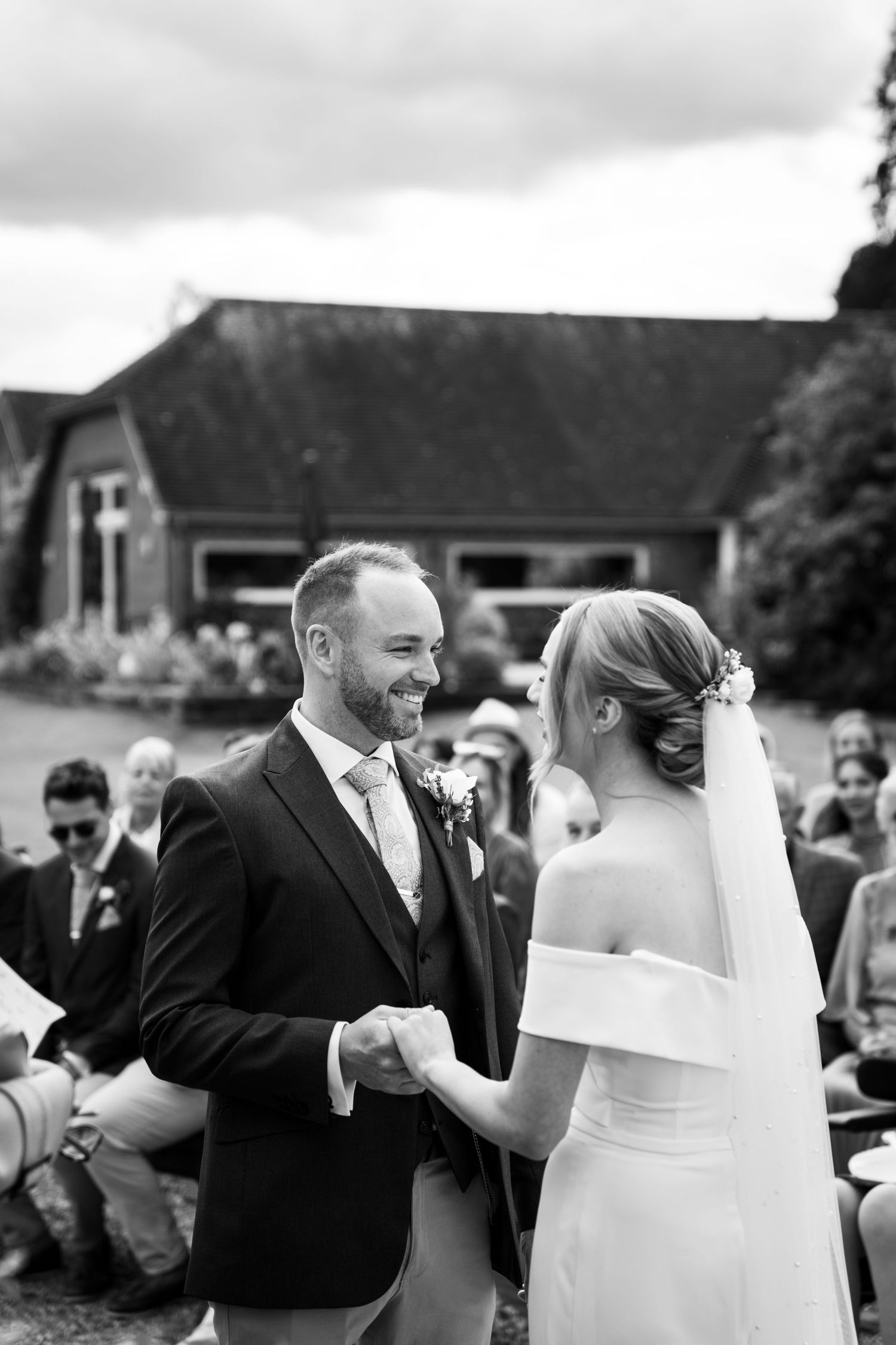 Bride and Groom holding hands, moments before their first kiss as Husband and Wife. an old converted barn sits in the background.