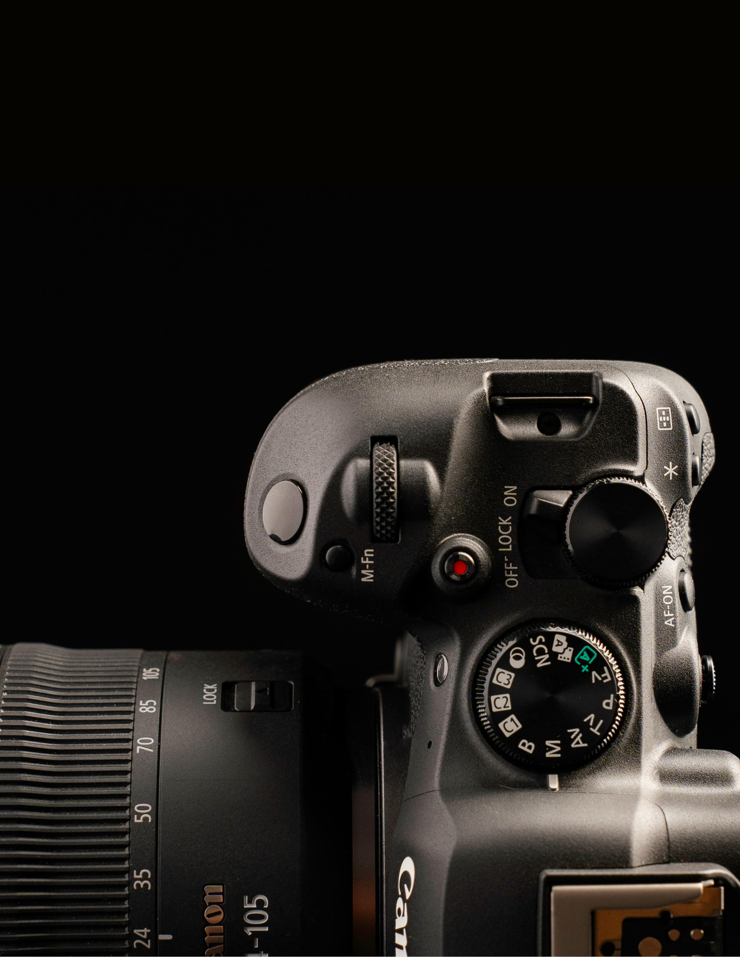 Close-up top view of a Canon DSLR camera with 18-105mm lens, showing mode dial and controls on black background.