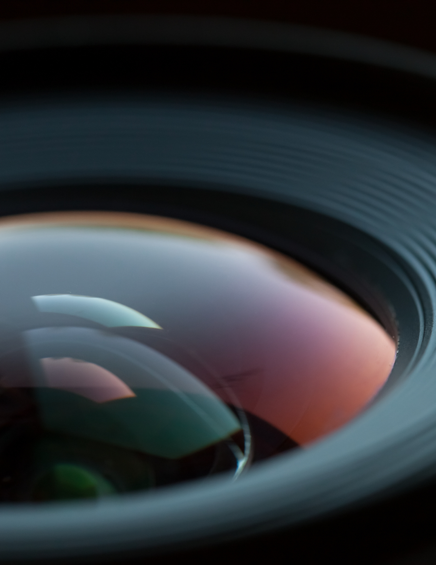 Close-up macro shot of a camera lens with colorful light reflections on glass elements.