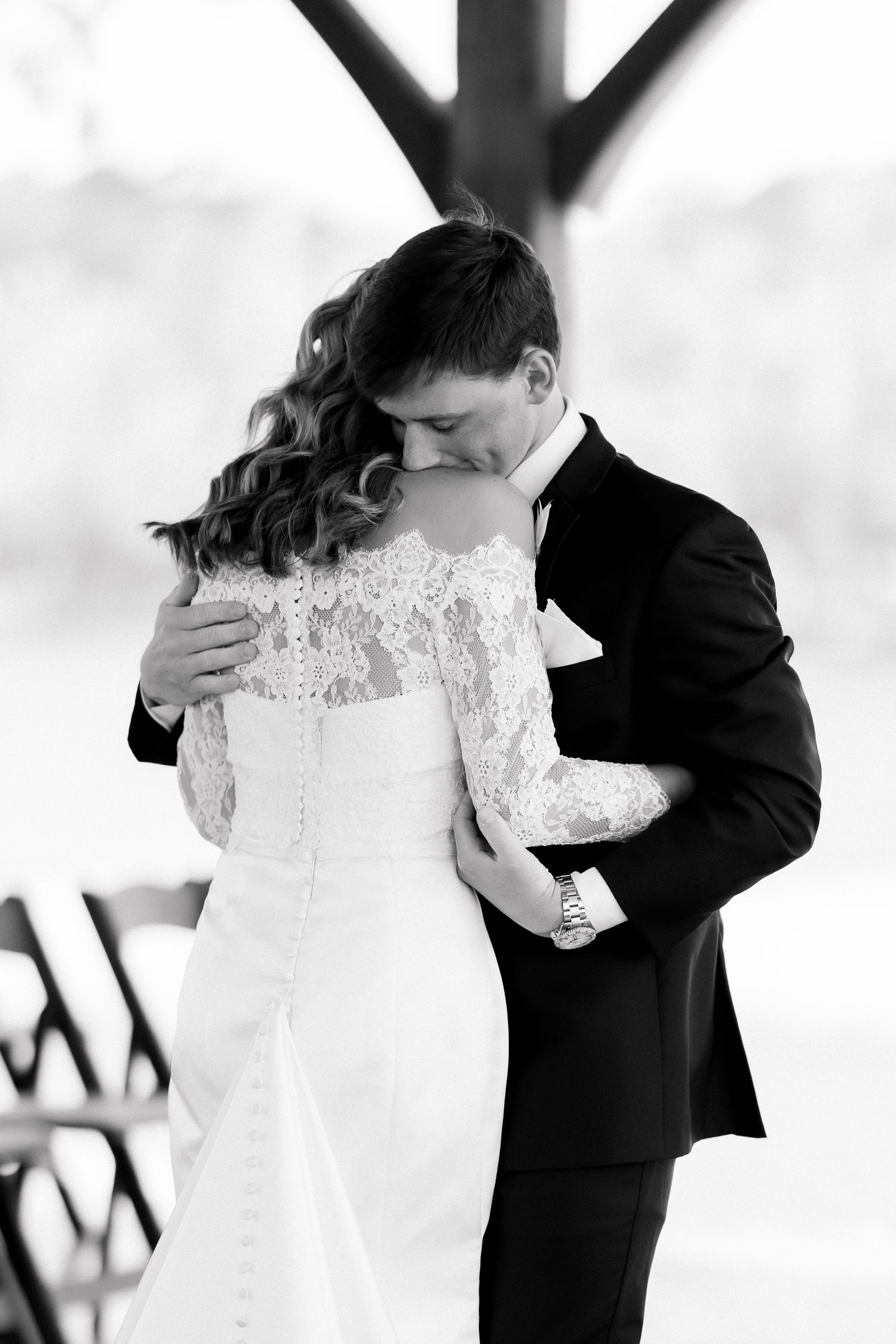 Black and white photo of a bride and groom sharing a tender kiss during their wedding ceremony.