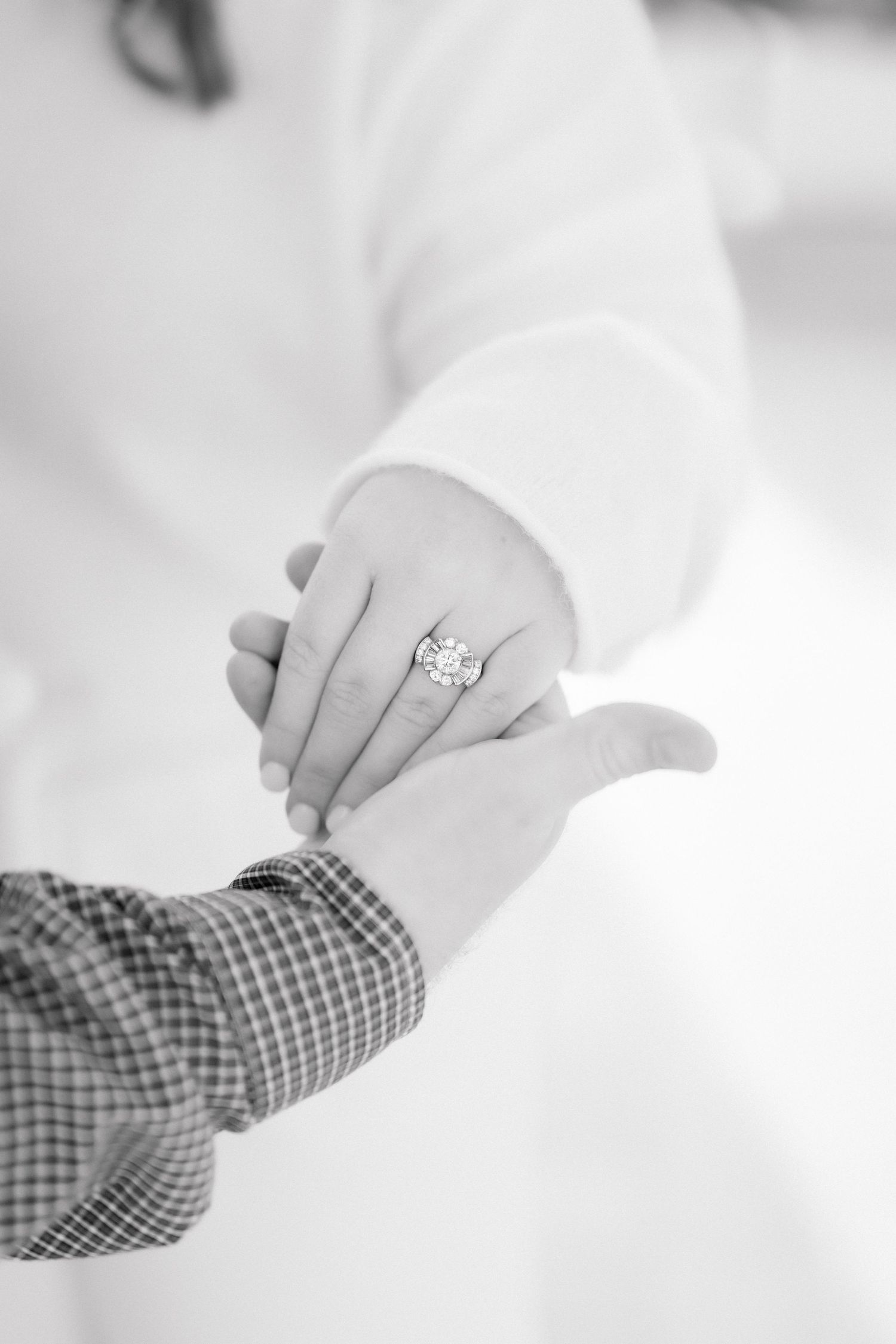 Black and white photo showing hands displaying an art deco heirloom engagement ring.