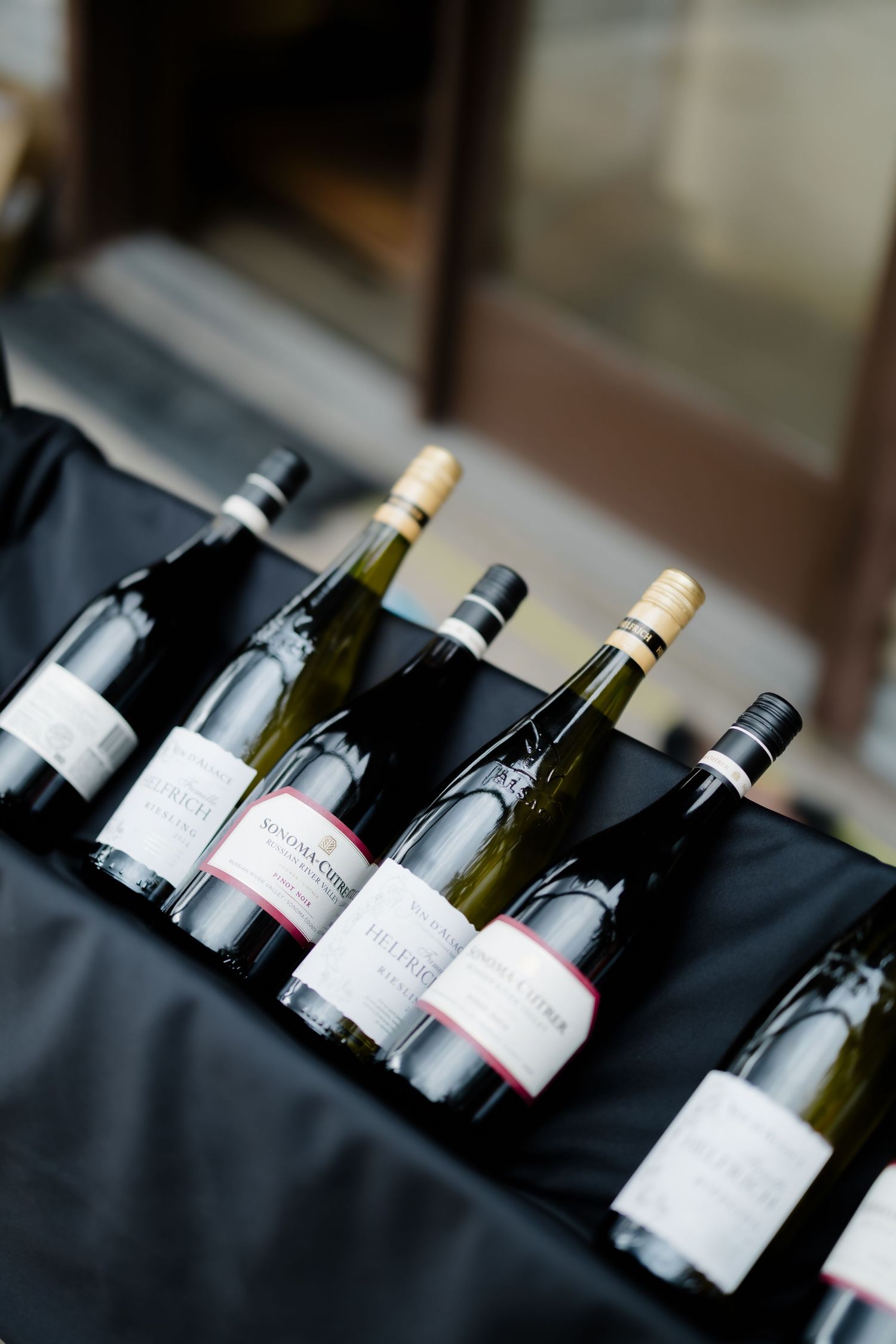 Multiple white wine bottles displayed on a black tablecloth at an elegant wine tasting event.